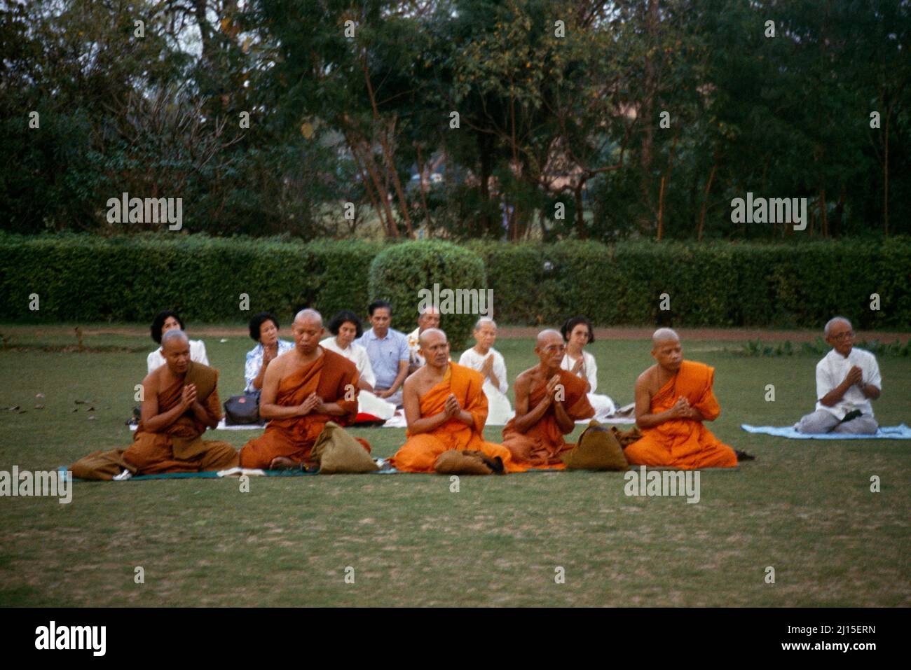 Sarnath India monjes y seguidores budistas orando en el parque de ciervos de Dusk Foto de stock