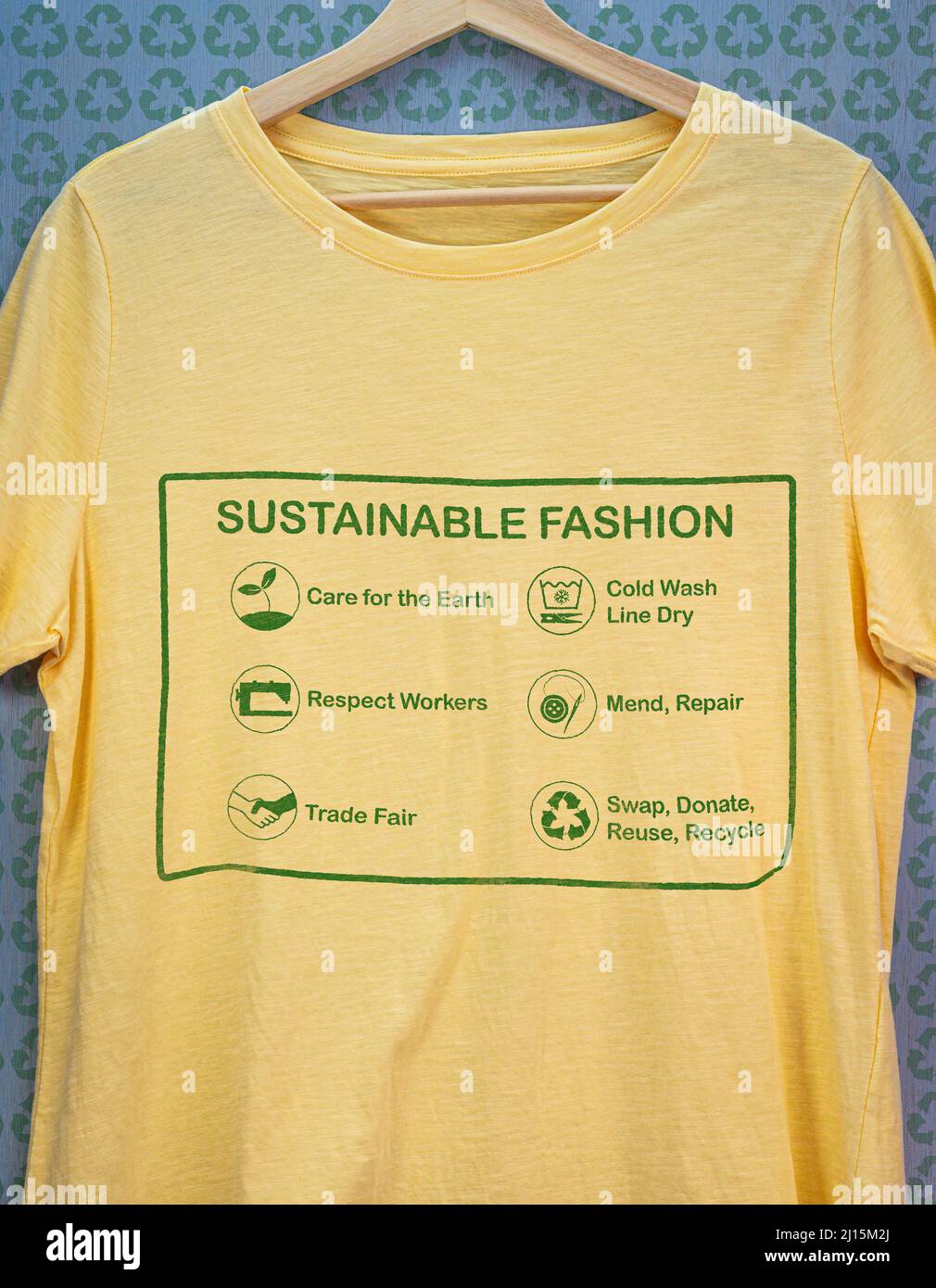 Camiseta en percha con etiqueta de moda sostenible, cuidado de la tierra, respeto por los trabajadores, feria comercial, reparar y reparar, reutilizar, intercambiar o donar Foto de stock