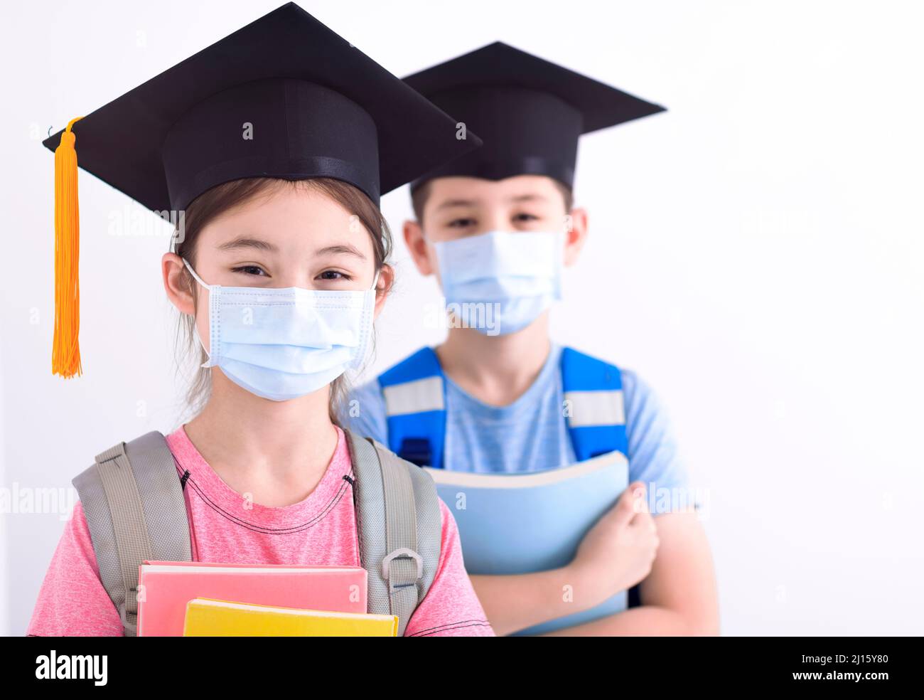 Niños de graduación que usan mascarilla facial para prevenir el coronavirus o covid-19 Foto de stock
