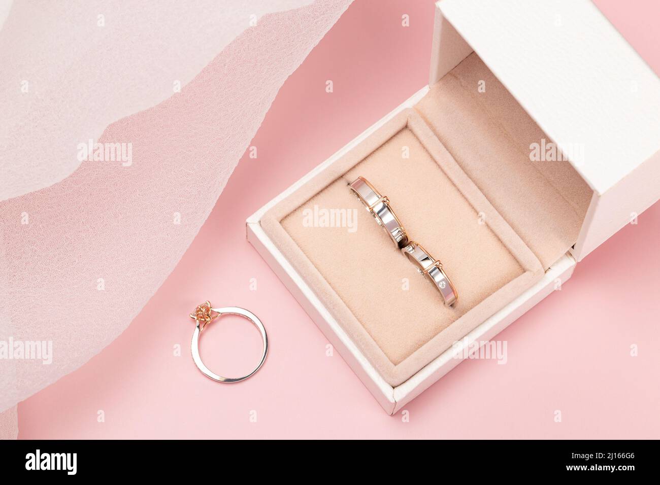 anillo de boda, anillo de compromiso en una caja tomada sobre un fondo rosa decorado con motivos e imágenes del día de la boda Foto de stock