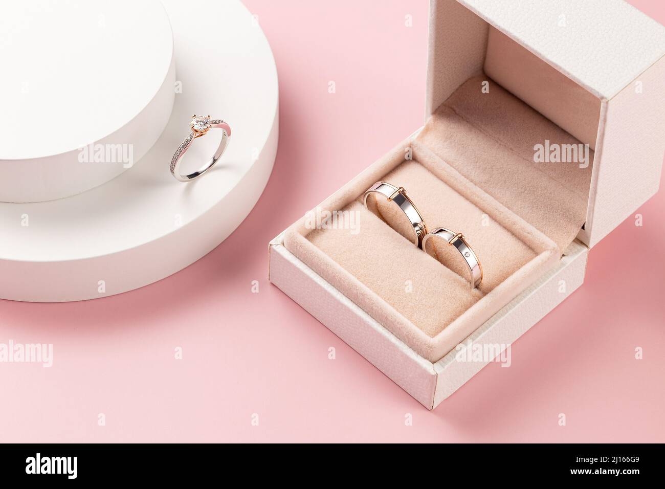 anillo de boda, anillo de compromiso en una caja tomada sobre un fondo rosa decorado con motivos e imágenes del día de la boda Foto de stock