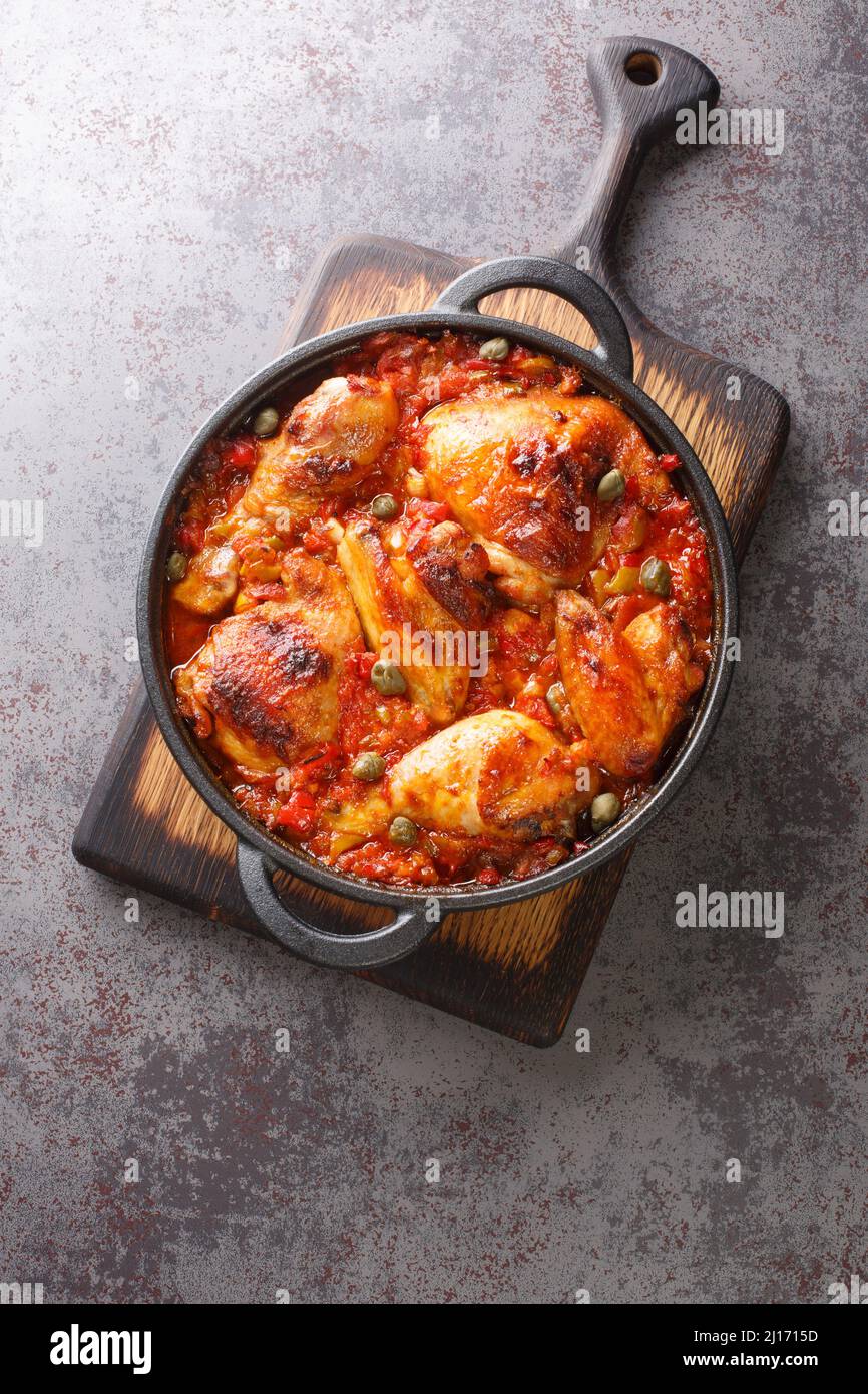 Pollo horneado con salsa de sofrito vegetal en una sartén sobre la mesa. Vista vertical superior desde arriba Foto de stock
