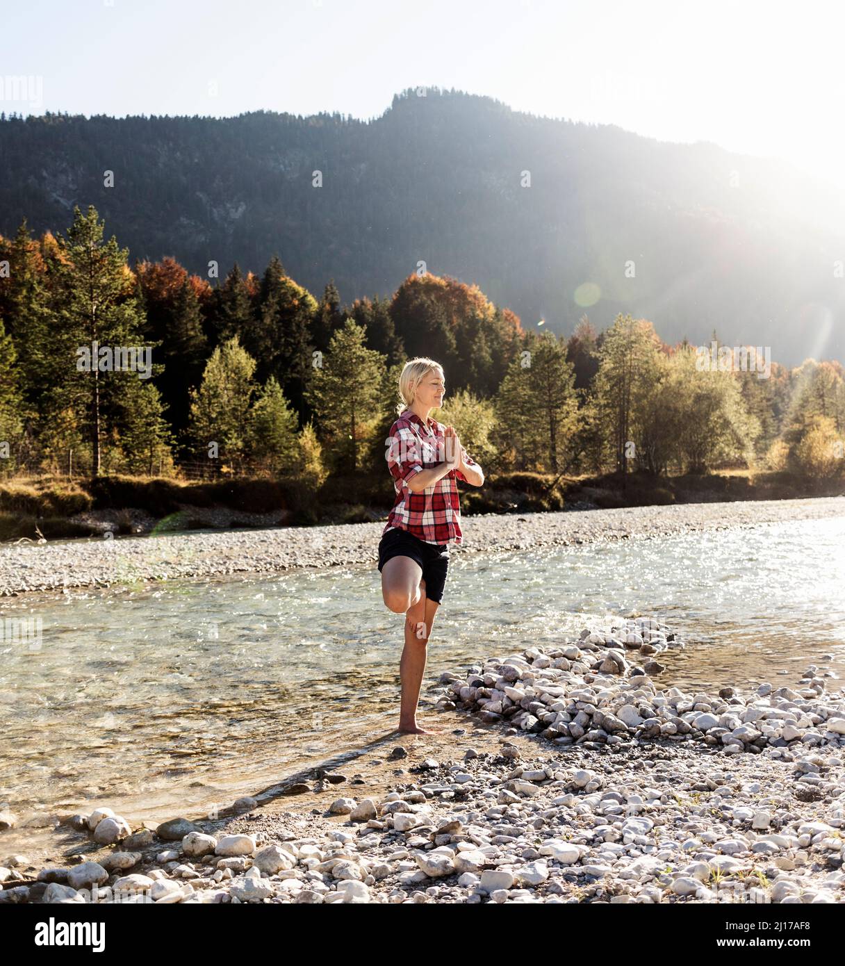 Austria, Alpes, mujer practicando yoga en un arroyo de montaña Foto de stock