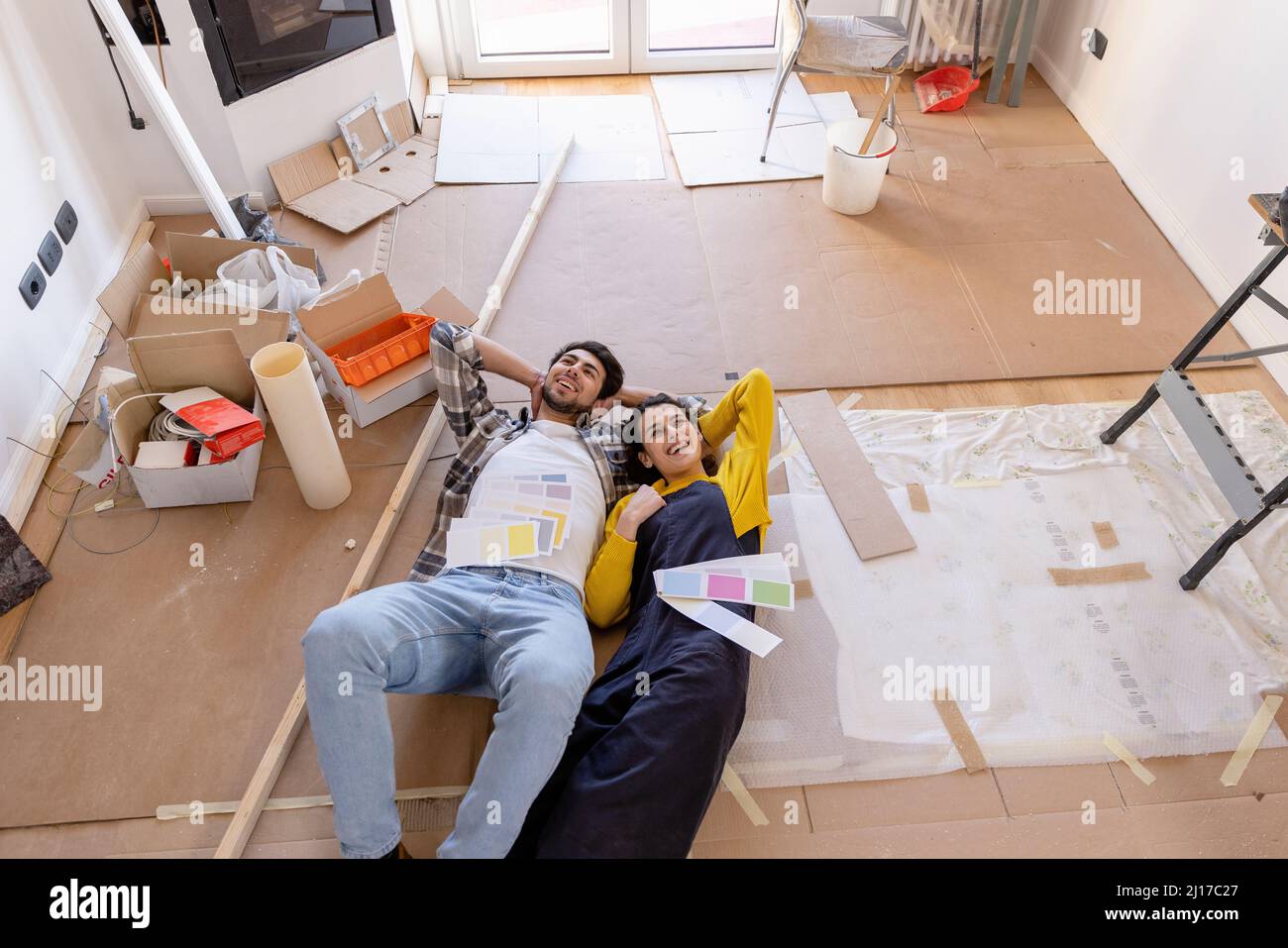 Joven pareja de día soñando con relojes de color en casa obras de renovación Foto de stock