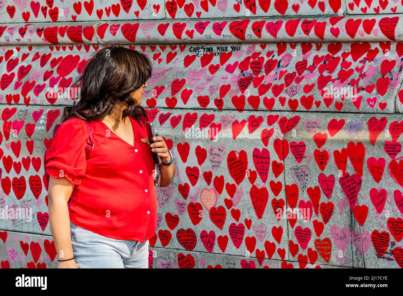 Londres, Reino Unido. 23rd Mar, 2022. El segundo aniversario del primer Lockdown - la gente todavía visita el muro nacional Covid Memorial a las afueras del Hospital St Thomas. Familiares y amigos de algunos de los más de ciento ochenta mil personas que han perdido la vida a Covid-19 han atraído corazones a mano en un muro frente al Parlamento de Londres. Fue organizado por las Familias para la Justicia de Covid-19. Crédito: Guy Bell/Alamy Live News Foto de stock