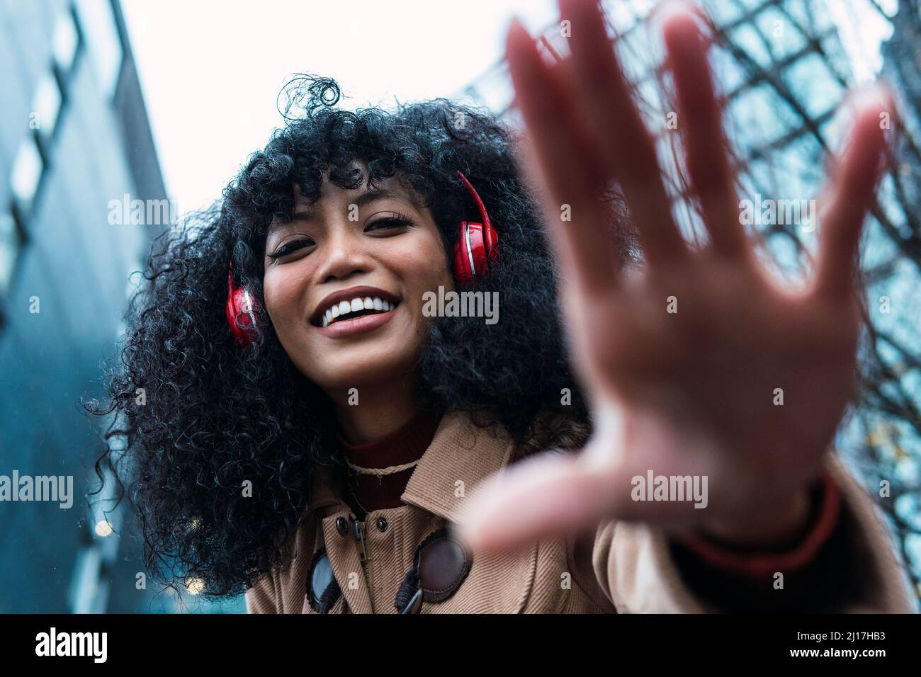 Hermosa mujer feliz escuchando música a través de auriculares inalámbricos gesturing Foto de stock
