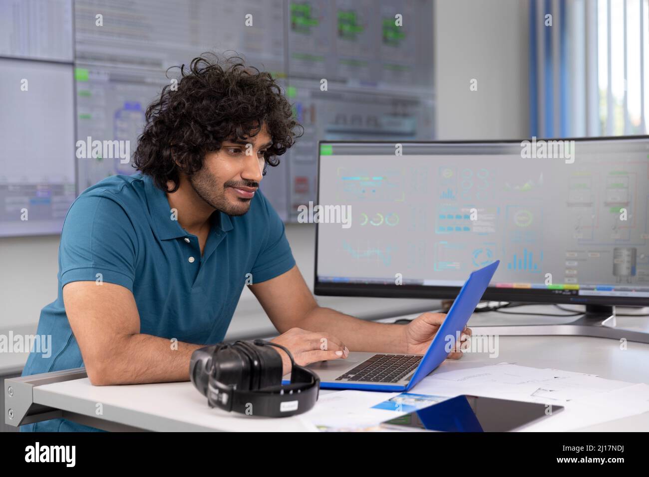 Técnico que utiliza un ordenador portátil en el escritorio de la sala de control Foto de stock