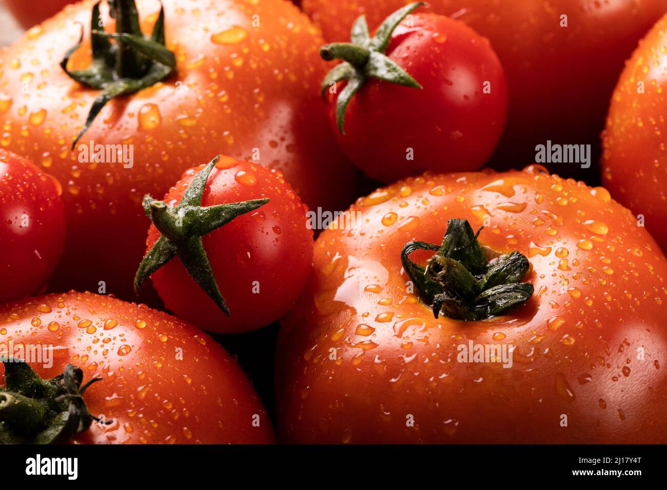 Toma completa de gotas de agua sobre tomates rojos frescos Foto de stock