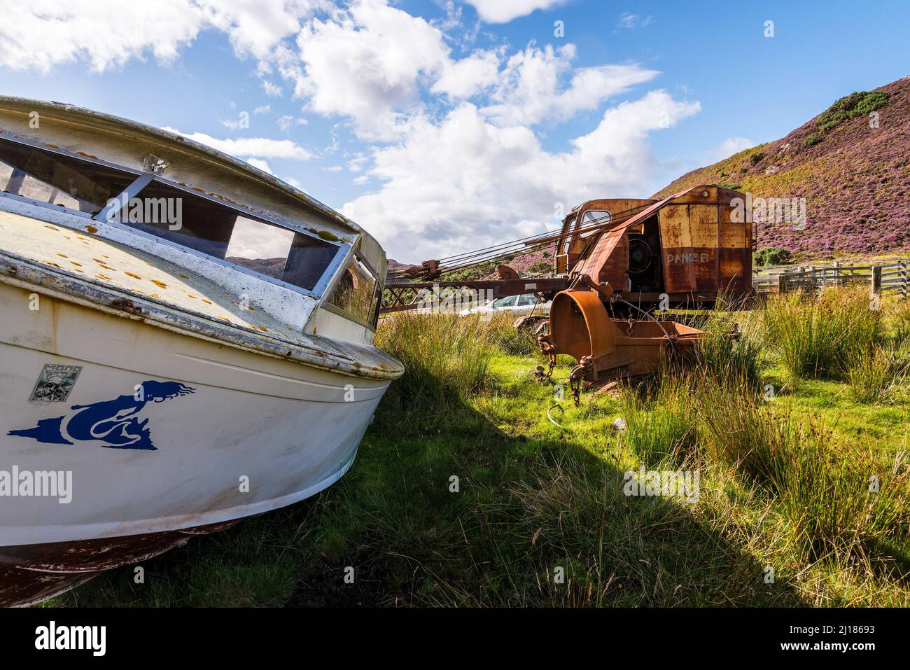 El sol brilla en un viejo barco y una vieja grúa que se sientan abandonados en el campo cerca de Skerray en Escocia. Foto de stock