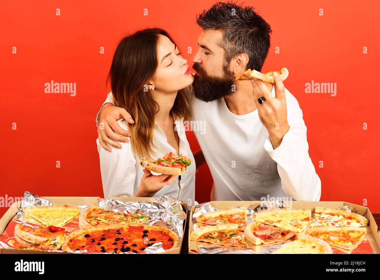 Pareja amorosa comiendo pizza y besando. Concepto de amor. Feliz familia cenar en casa. Comida rápida Foto de stock