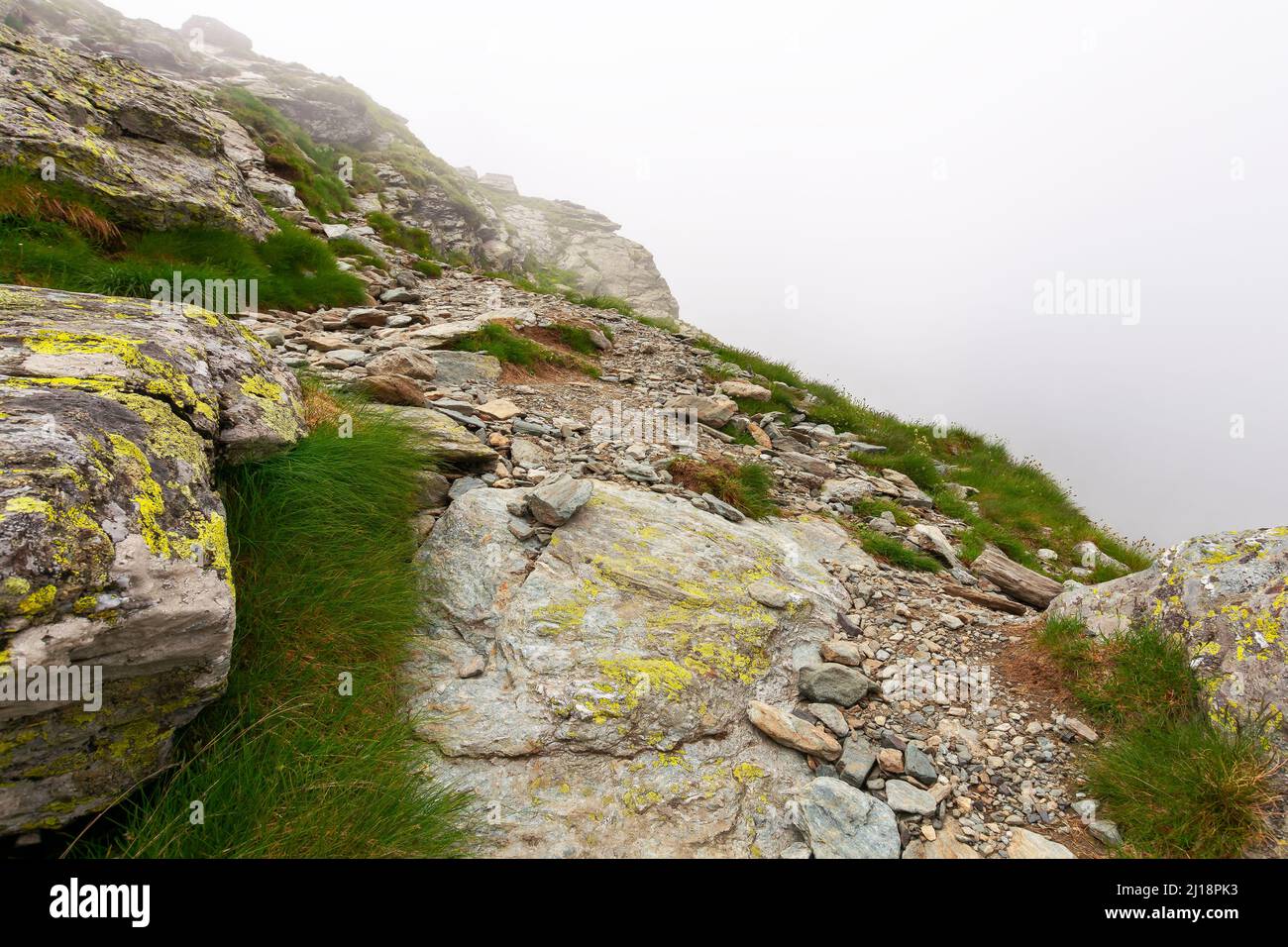 escarpadas laderas de las montañas de fagaras en niebla. enormes rocas sobre colinas cubiertas de hierba. viajar rumania en verano Foto de stock