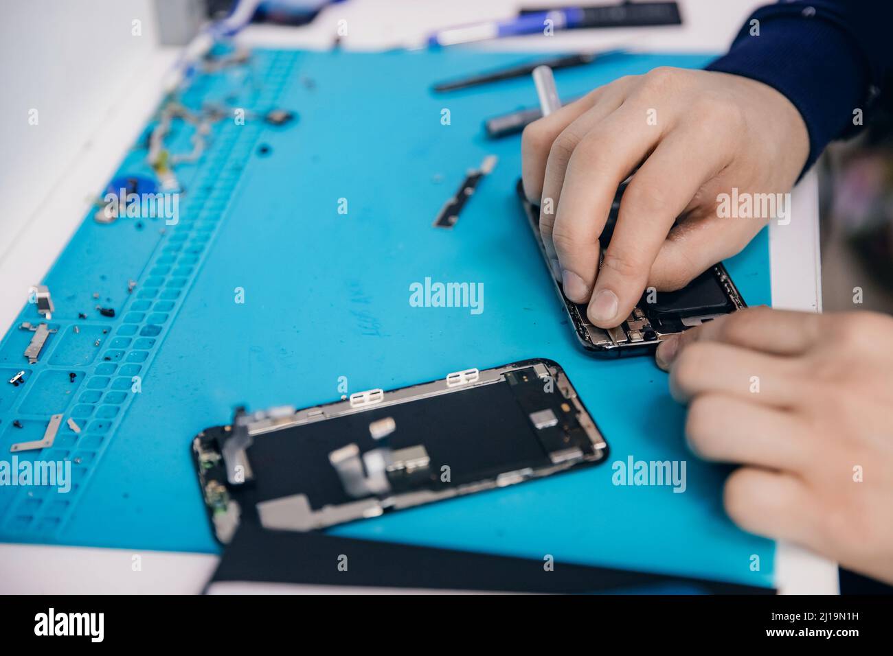 Reparar el teléfono móvil moderno, el maestro desensambla la caja para