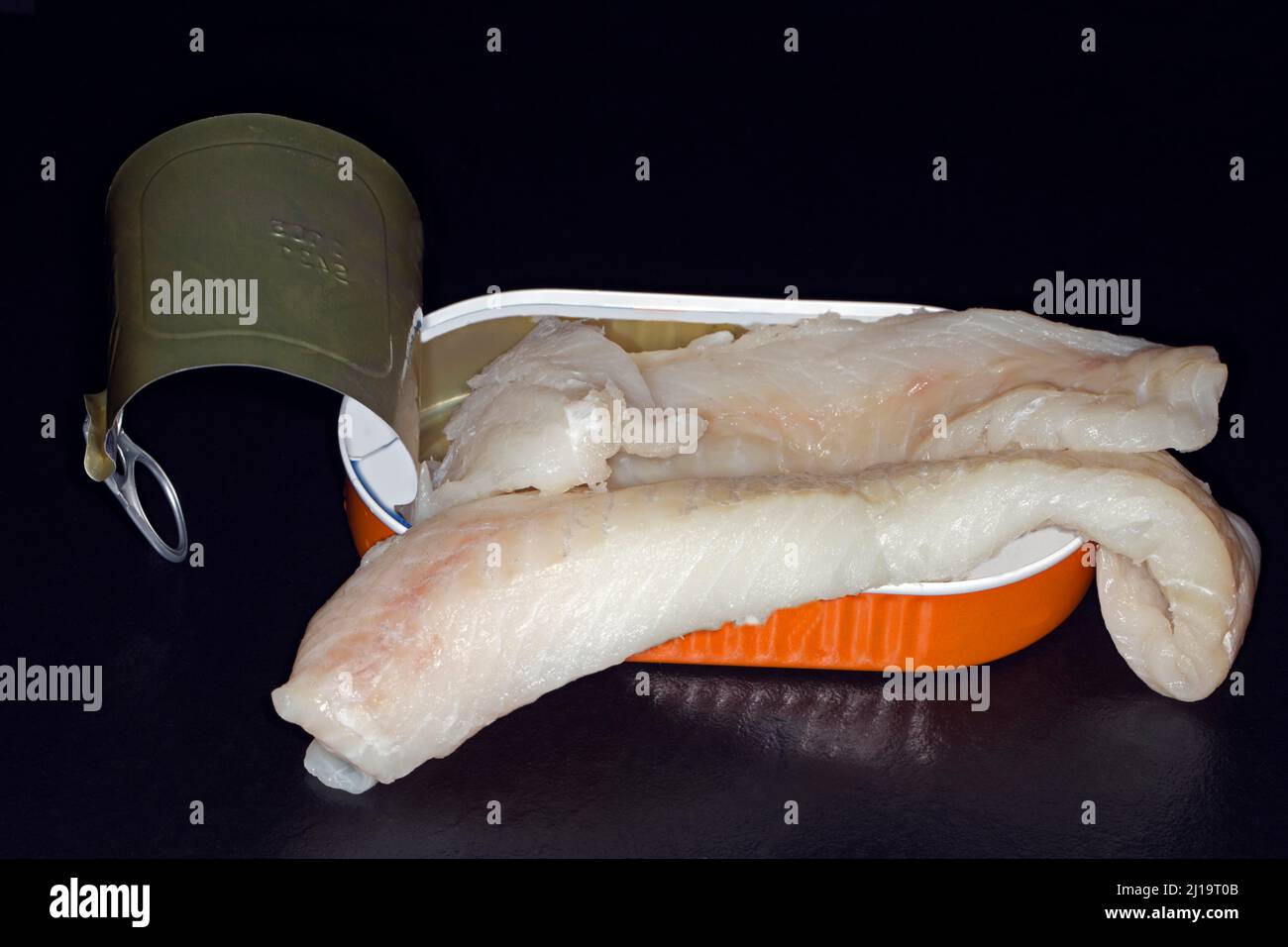 Filetes de bacalao del atlántico (Gadus morhua), skrei, tumbados en una lata de aluminio abierta, fotografía de estudio con fondo negro Foto de stock