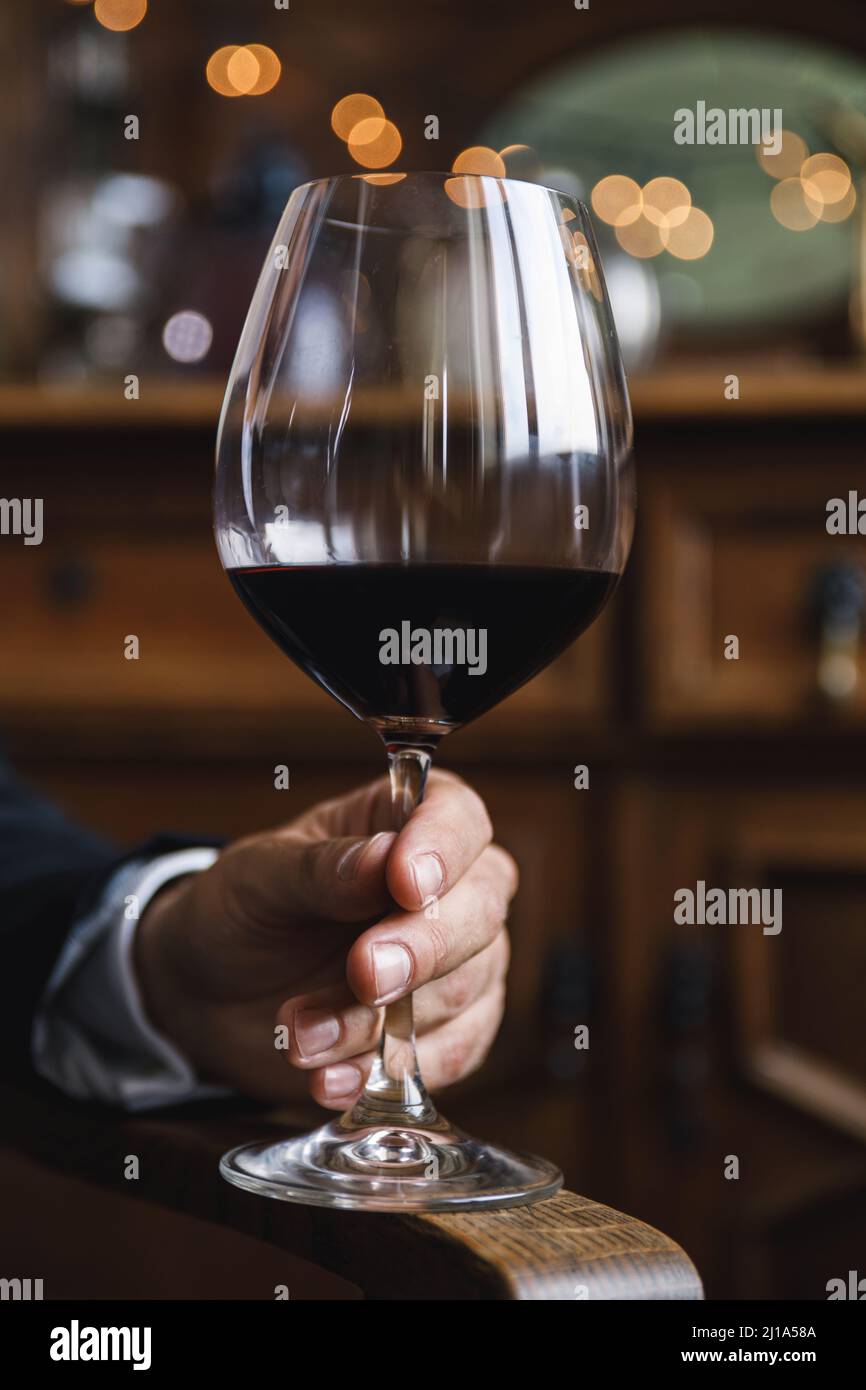 Mano masculina con un vaso de vino tinto Fotografía de stock - Alamy