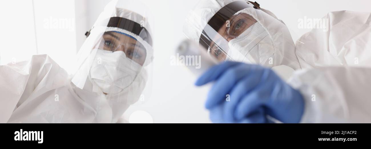 Médico en trajes médicos de protección poniendo la máscara en el paciente y mide la temperatura de la vista inferior Foto de stock