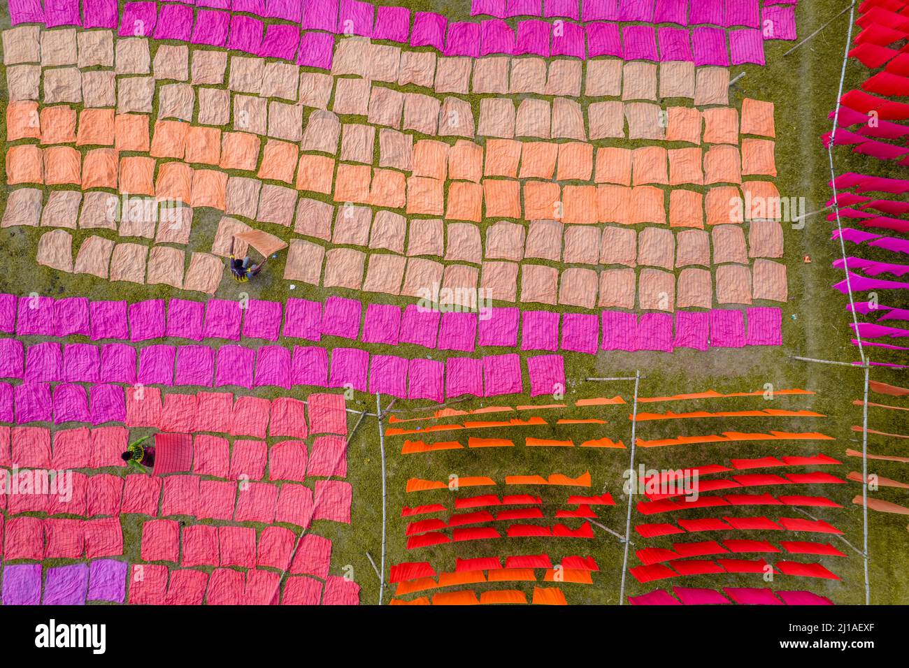 Narayanganj, Dhaka, Bangladesh. 24th Mar, 2022. Miles de paños de colores se ponen para secar bajo el sol caliente. Después de que la tela se tiñe, se extiende hacia fuera en un campo, cubriendo aproximadamente 10.000 pies cuadrados, en la aldea de Batik en Narayanganj, Bangladesh.Una vez que están secos - que toma generalmente cuatro horas - se hacen en la ropa que se venden en todo el mundo. (Imagen de crédito: © Mustasinur Rahman Alvi/ZUMA Press Wire) Crédito: ZUMA Press, Inc./Alamy Live News Foto de stock