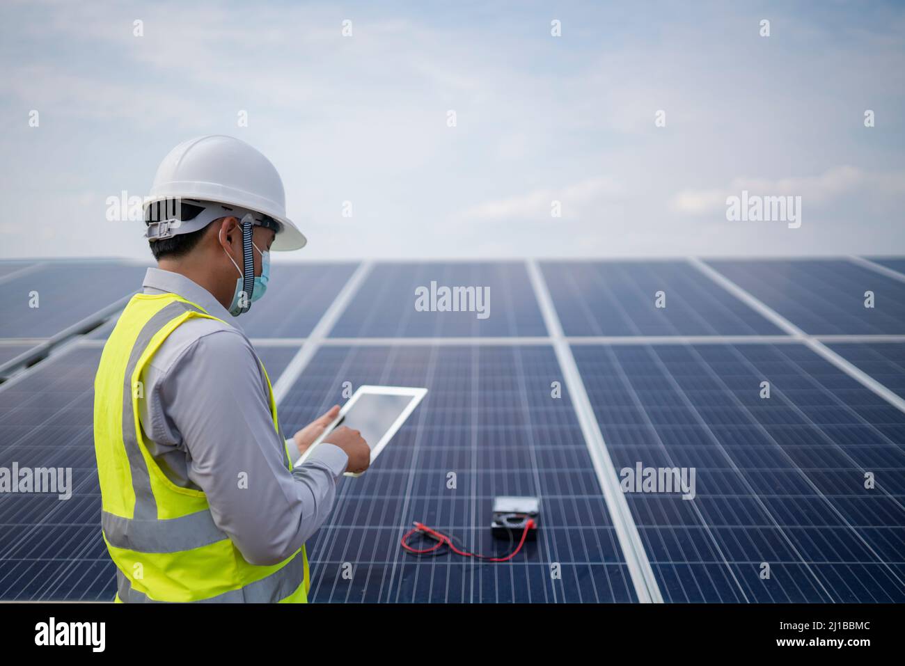 Joven ingeniero que trabaja en el panel solar de la central eléctrica Foto de stock
