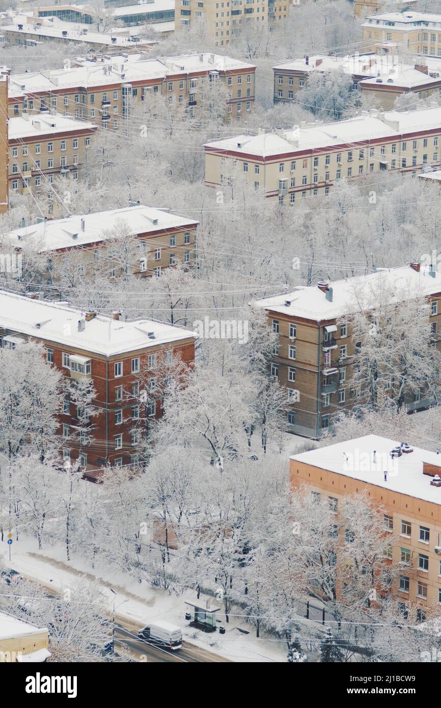 Techos cubiertos de nieve de los edificios de apartamentos después de nevar el día anterior. Carretera de nieve entre casas. La nieve esponjosa se encuentra en las ramas de los árboles. Foto de stock