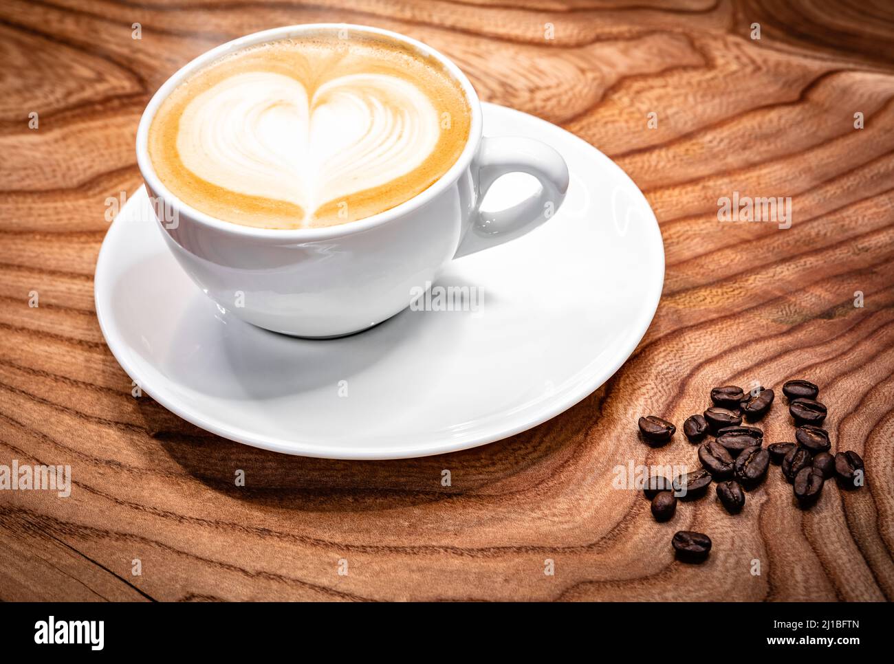 Taza de café con leche en forma de corazón, granos de café en la mesa  Fotografía de stock - Alamy