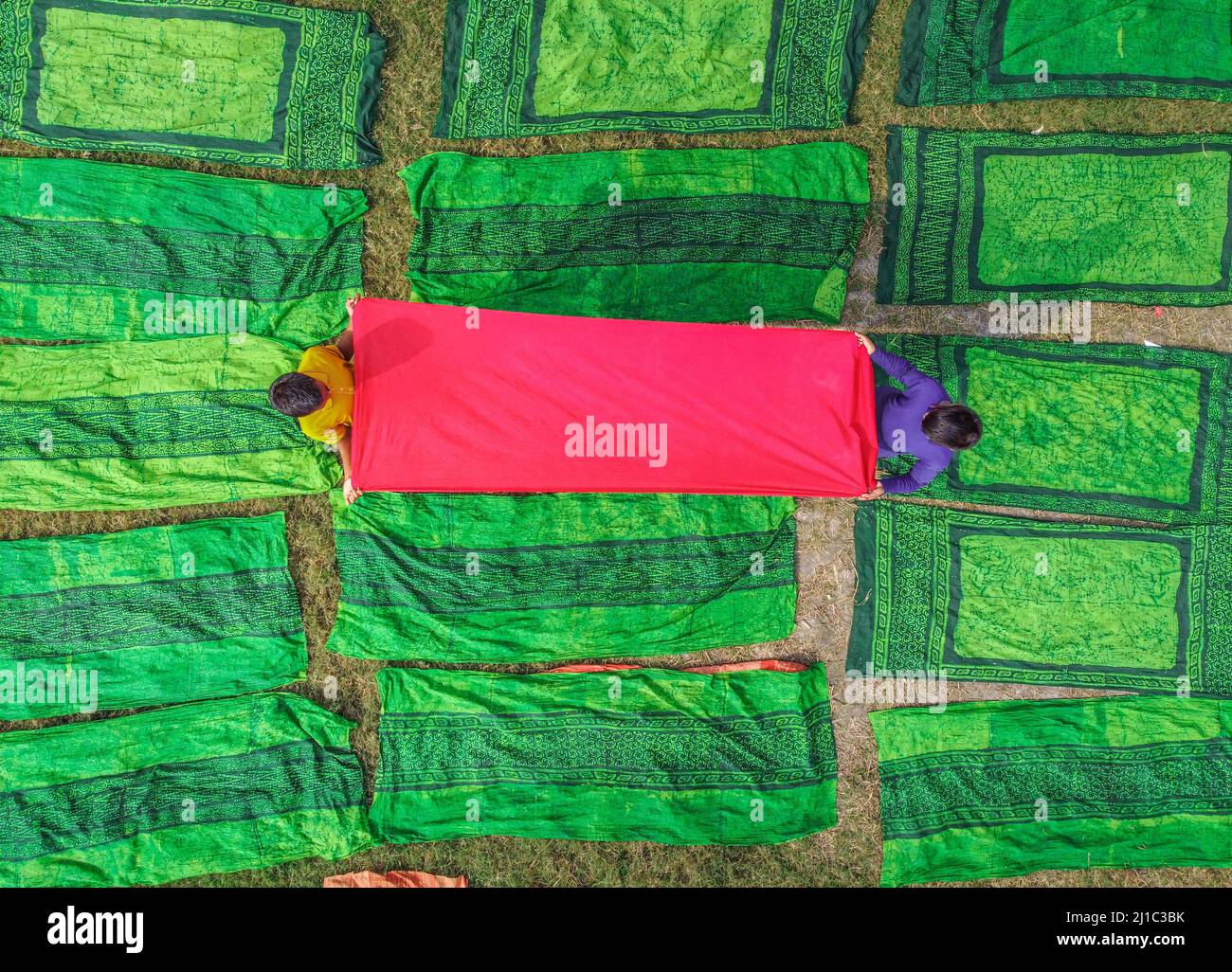 Narayanganj, Dhaka, Bangladesh. 24th Mar, 2022. Miles de paños de colores se ponen para secar bajo el sol caliente. Una vez teñida la tela, se extiende sobre un campo, que cubre aproximadamente 10.000 pies cuadrados, en la aldea de Batik en Narayanganj, Bangladesh. Una vez que están secos - que normalmente toma cuatro horas - se hacen en la ropa que se venden en todo el mundo. (Imagen de crédito: © Mustasinur Rahman Alvi/ZUMA Press Wire) Foto de stock