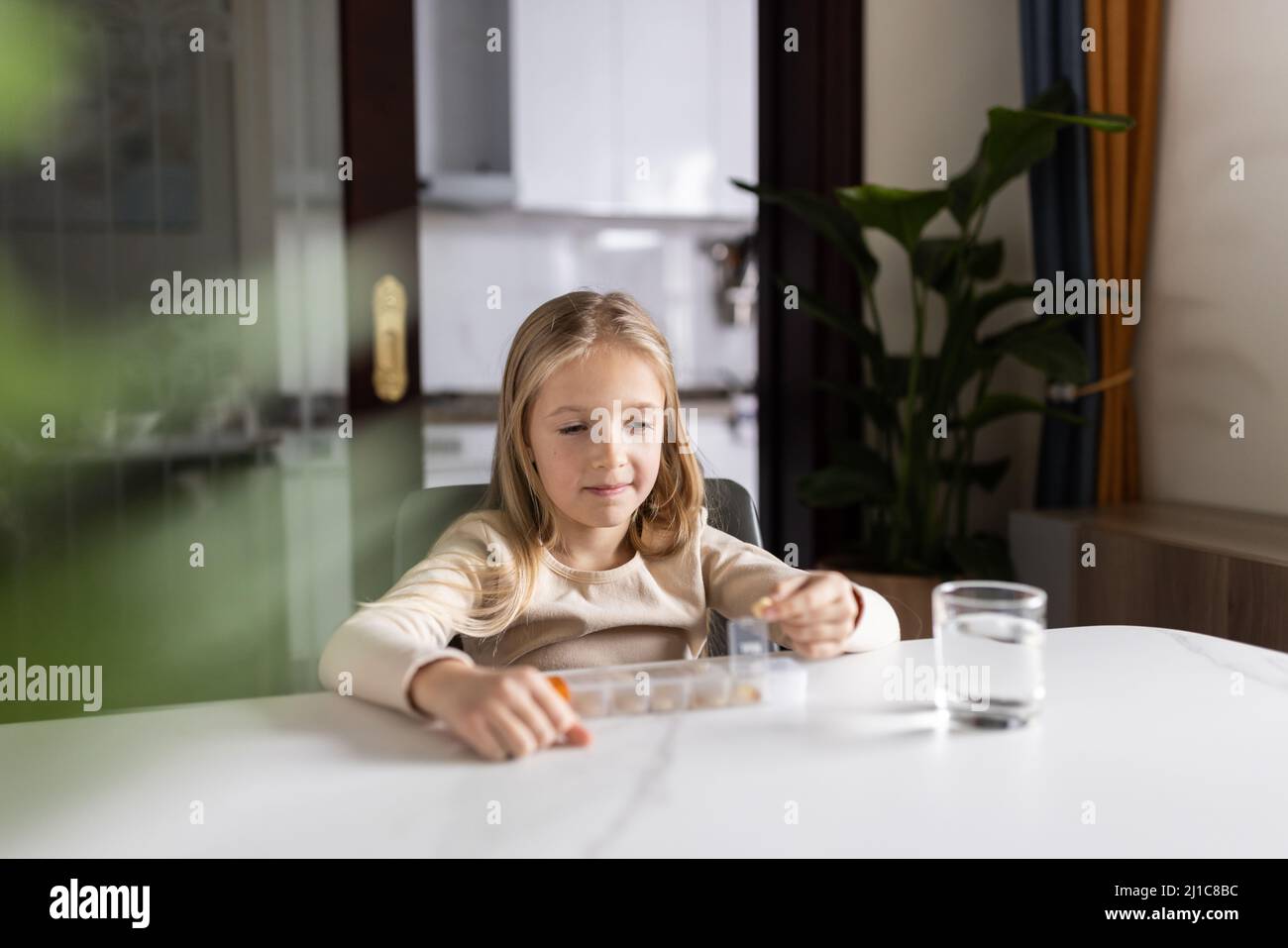 Niña Caucásica en pijamas tomando vitamina omega-3 natural de la caja de  plástico en la cocina en casa temprano por la mañana. Un niño adorable toma  suplementos Fotografía de stock - Alamy