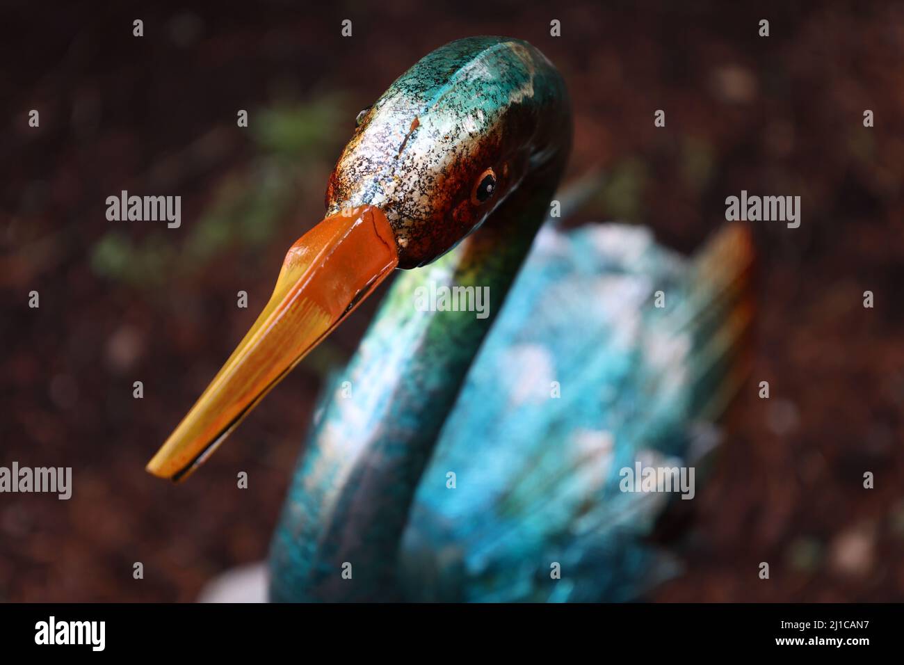 Decoración del patio de pájaro naranja y metal azul con corteza en un fondo borroso. Foto de stock