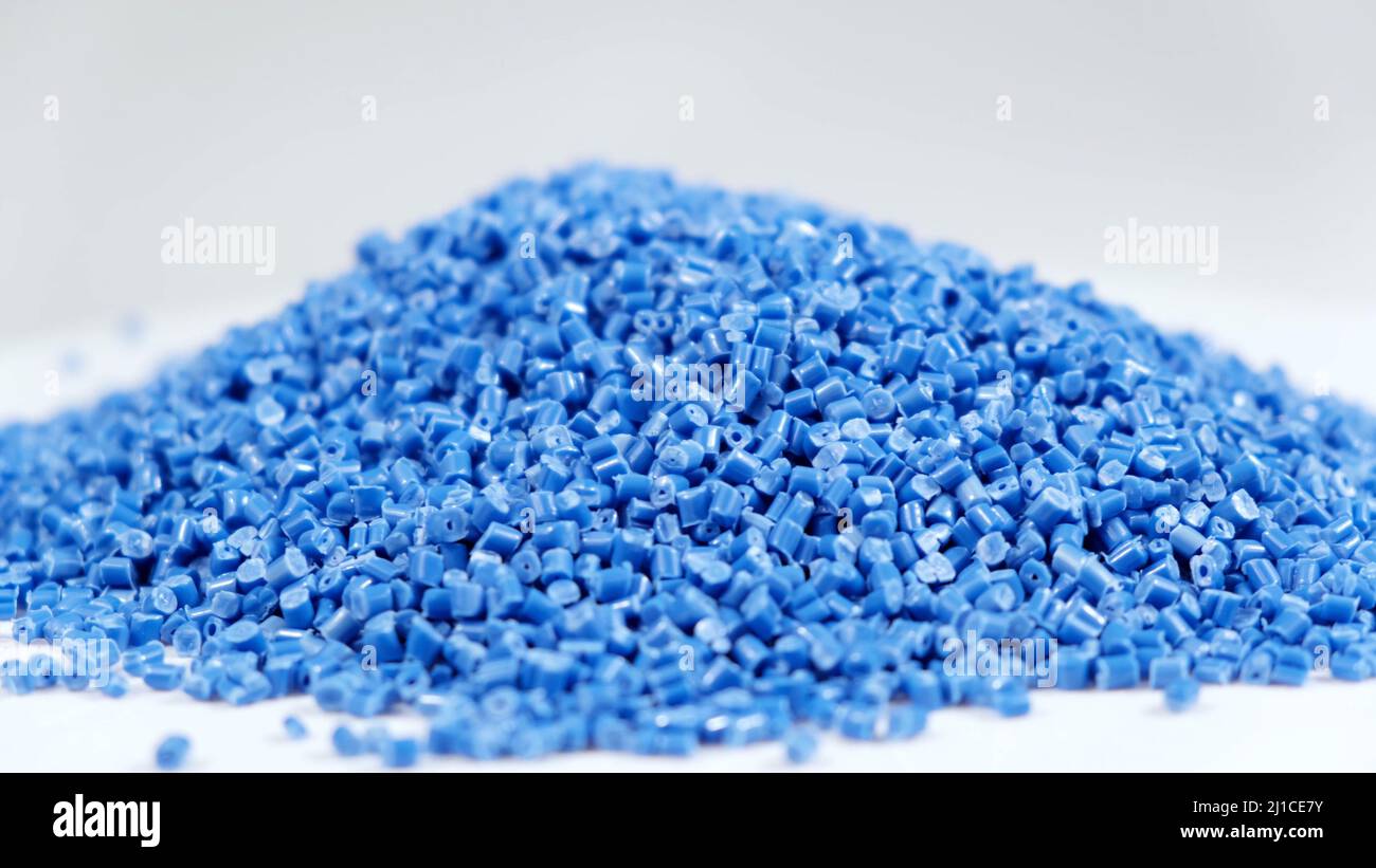 Gránulos secundarios de polipropileno, pellets de plástico azul se desmenuza a la mesa. Materias primas plásticas en gránulos para la industria. Resina polimérica Foto de stock