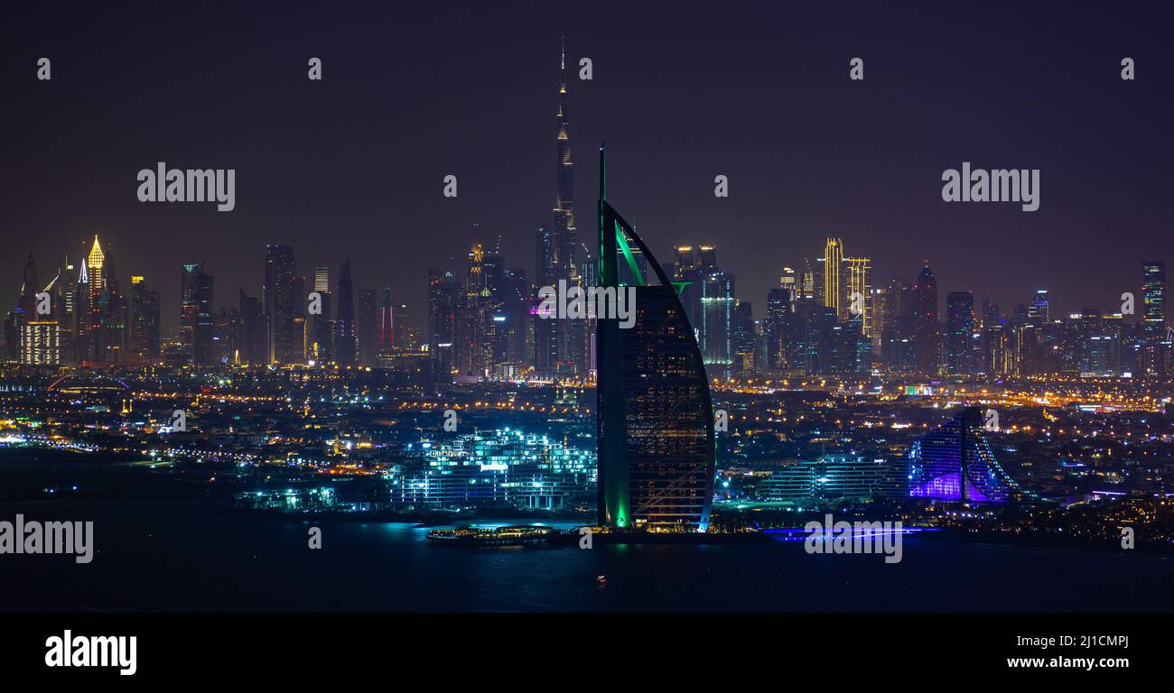 Dubai, EAU - 05 2021 dic: Vista nocturna del Burj Al Arab y del puerto deportivo de Dubai con el Burj Khalifa en la distancia Foto de stock