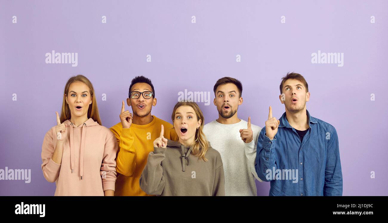 Grupo de jóvenes felices y diversas personas sorprendidas por una gran idea apuntando sus dedos hacia arriba Foto de stock