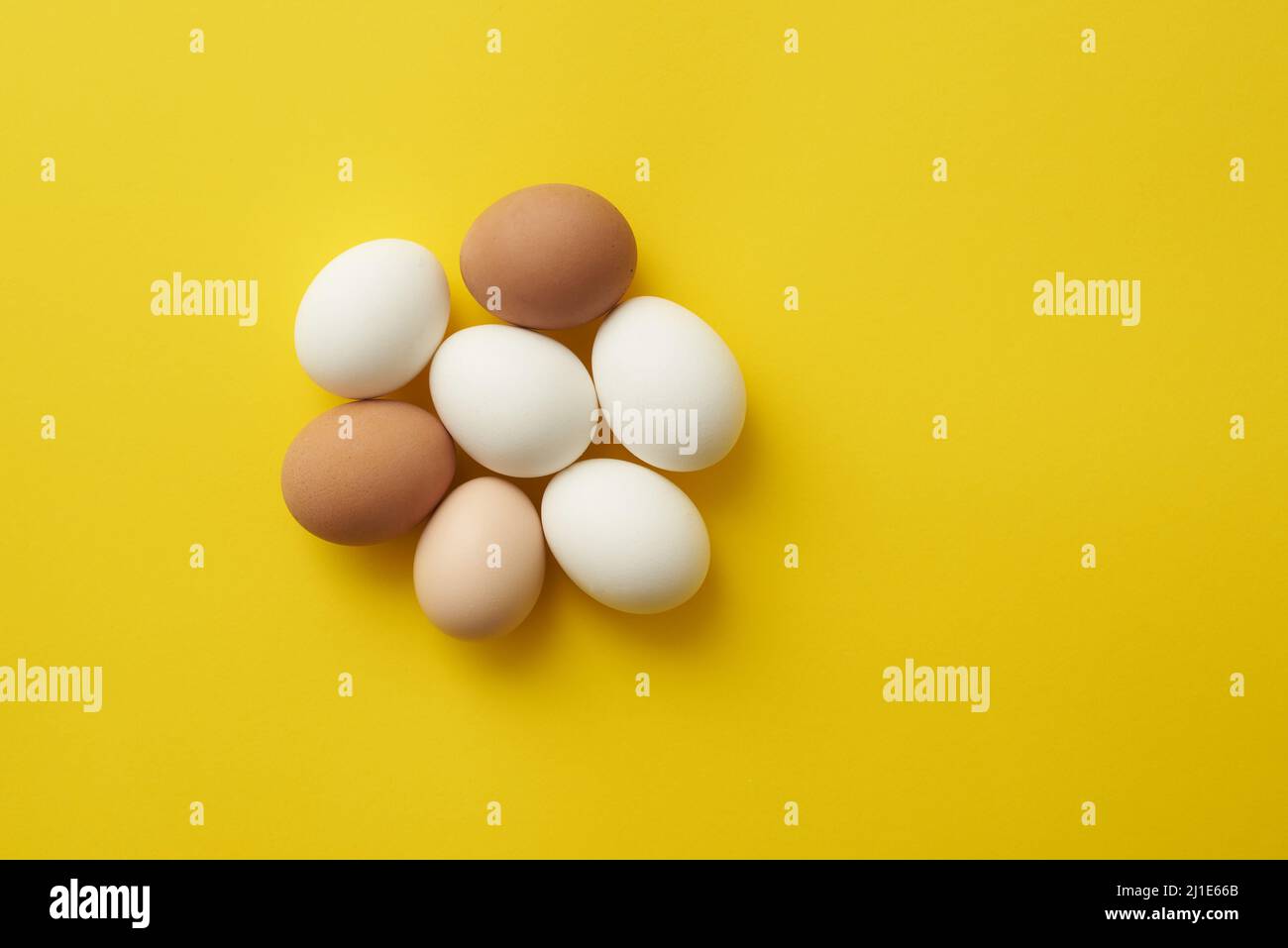 Huevos de pollo sobre fondo de papel amarillo Foto de stock