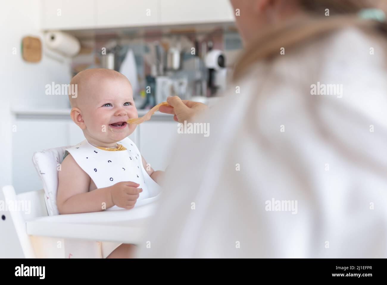 la primera alimentación del bebé, la mamá alimenta a un bebé con una cuchara Foto de stock