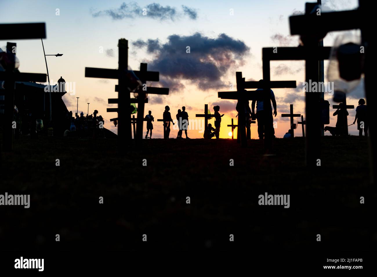 Silueta de personas y cruces fijadas en el suelo en honor de los muertos por covid-19. Puesta de sol en Salva Foto de stock