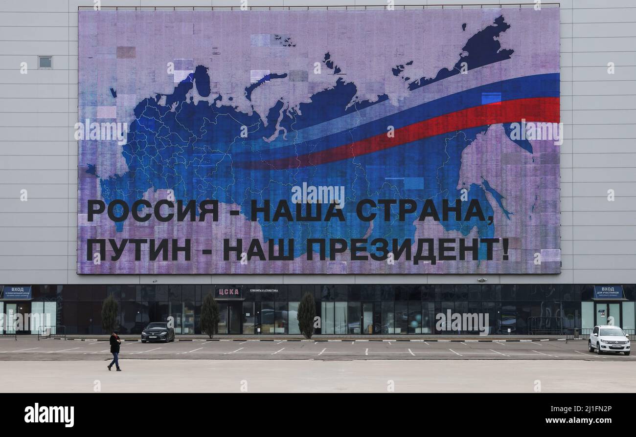 Un hombre pasa por una pantalla electrónica que muestra el mapa de Rusia y un eslogan: “Rusia es nuestro país, Putin es nuestro presidente”. En Moscú, Rusia, 25 de marzo de 2022. FOTÓGRAFO REUTERS/REUTERS Foto de stock