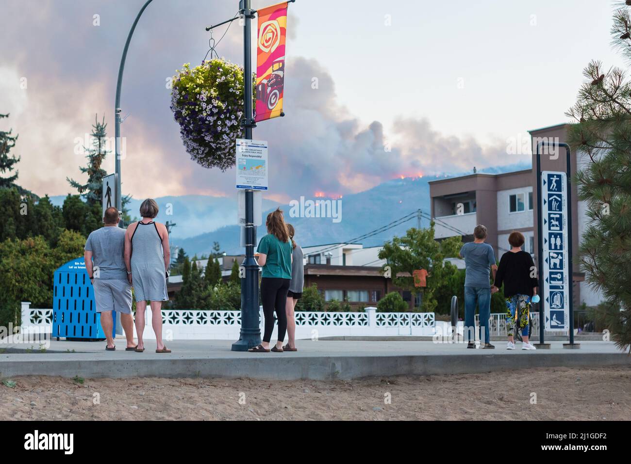 Penticton, BC/Canadá - 29 de agosto de 2021: Los peatones observan desde Lakeshore Drive como un incendio forestal se dispara en las colinas sobre la ciudad. Foto de stock