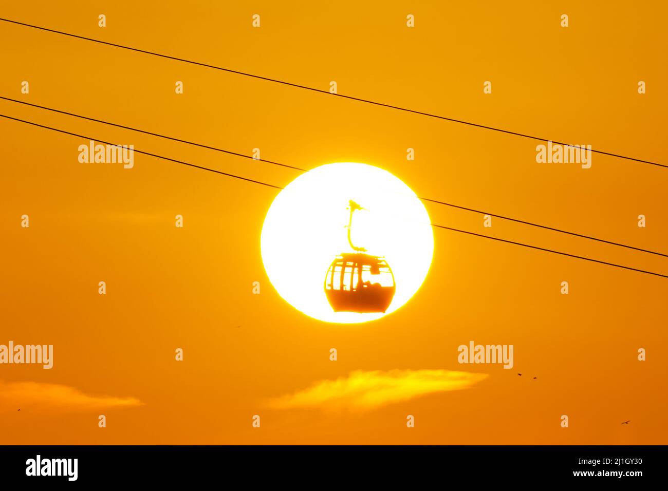 Londres, Reino Unido. 25th Mar, 2022. Clima en el Reino Unido: Sun se pone detrás del teleférico Emirates Air Line. Crédito: Marcin Rogozinski/Alamy Live News Foto de stock