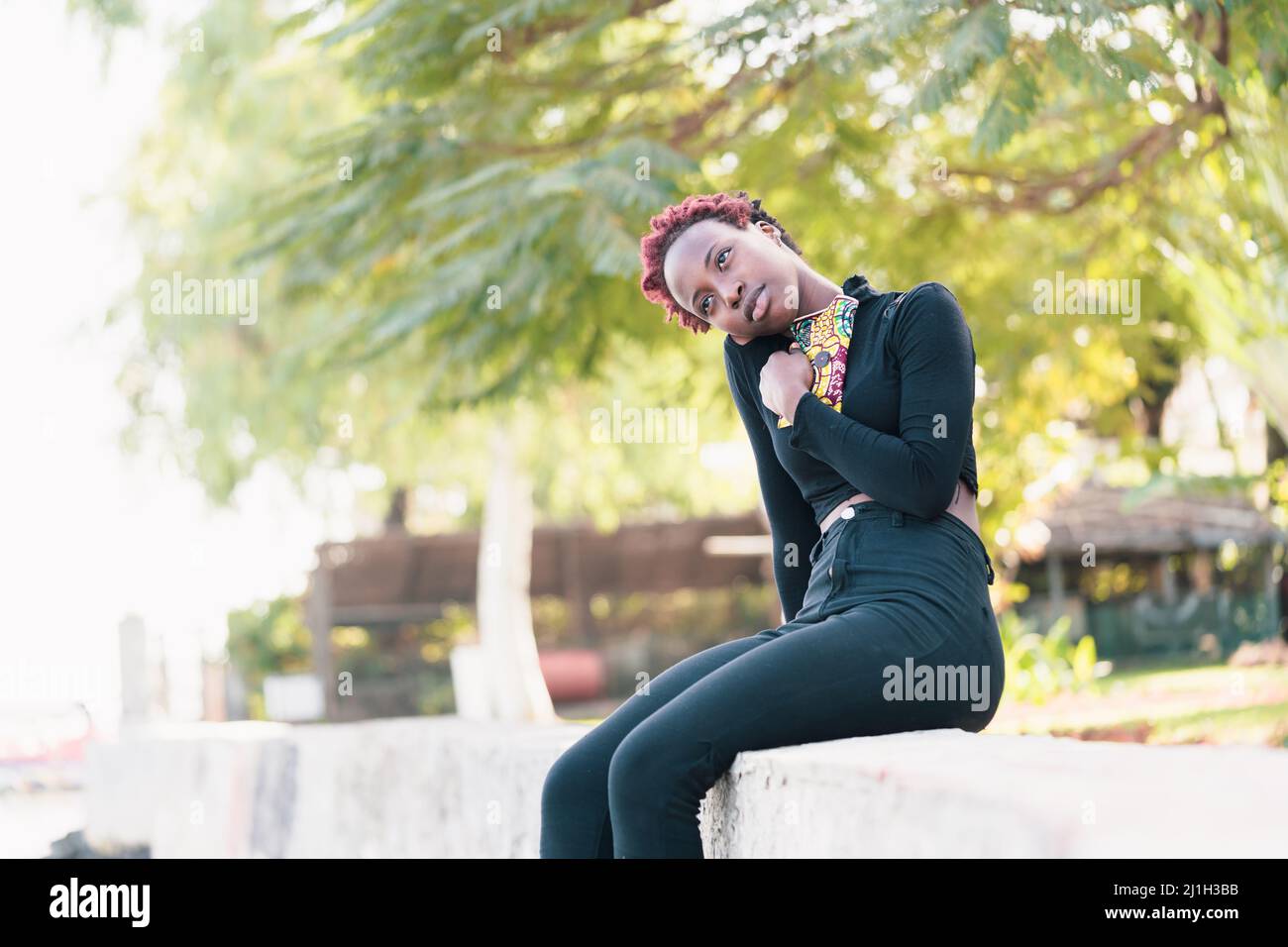 Mujer africana melancólica sentada en un parque, sintiéndose nostálgica, recordando recuerdos de su concepto de migración nacional. Foto de stock