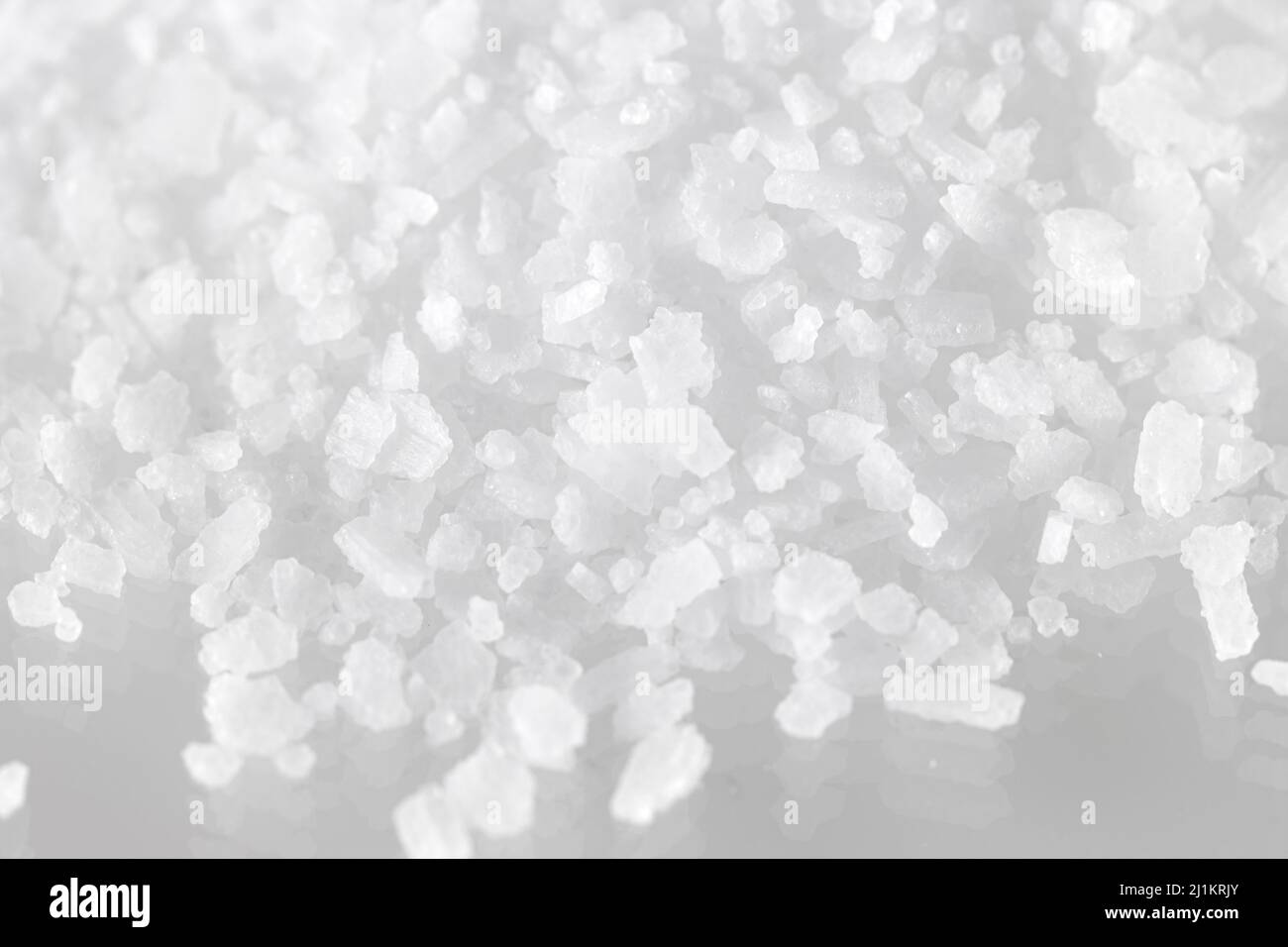 pila suelta de sal marina kosher sobre un suave fondo blanco reflectante con poca profundidad de campo Foto de stock