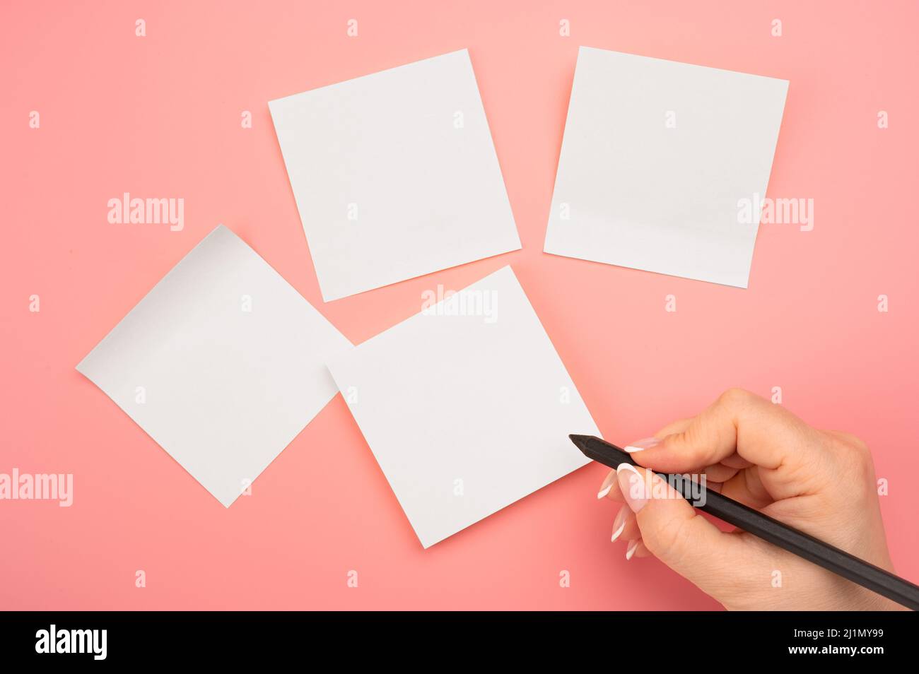 Papel de notas pegajoso de la maqueta. Notas escritas a mano lápiz negro sobre sticker blanco.pink background.woman mano escrito sobre notas adhesivas blancas. Gente de negocios m Foto de stock