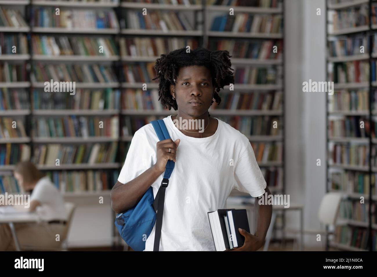 Un estudiante africano serio posando en la biblioteca del campus Foto de stock