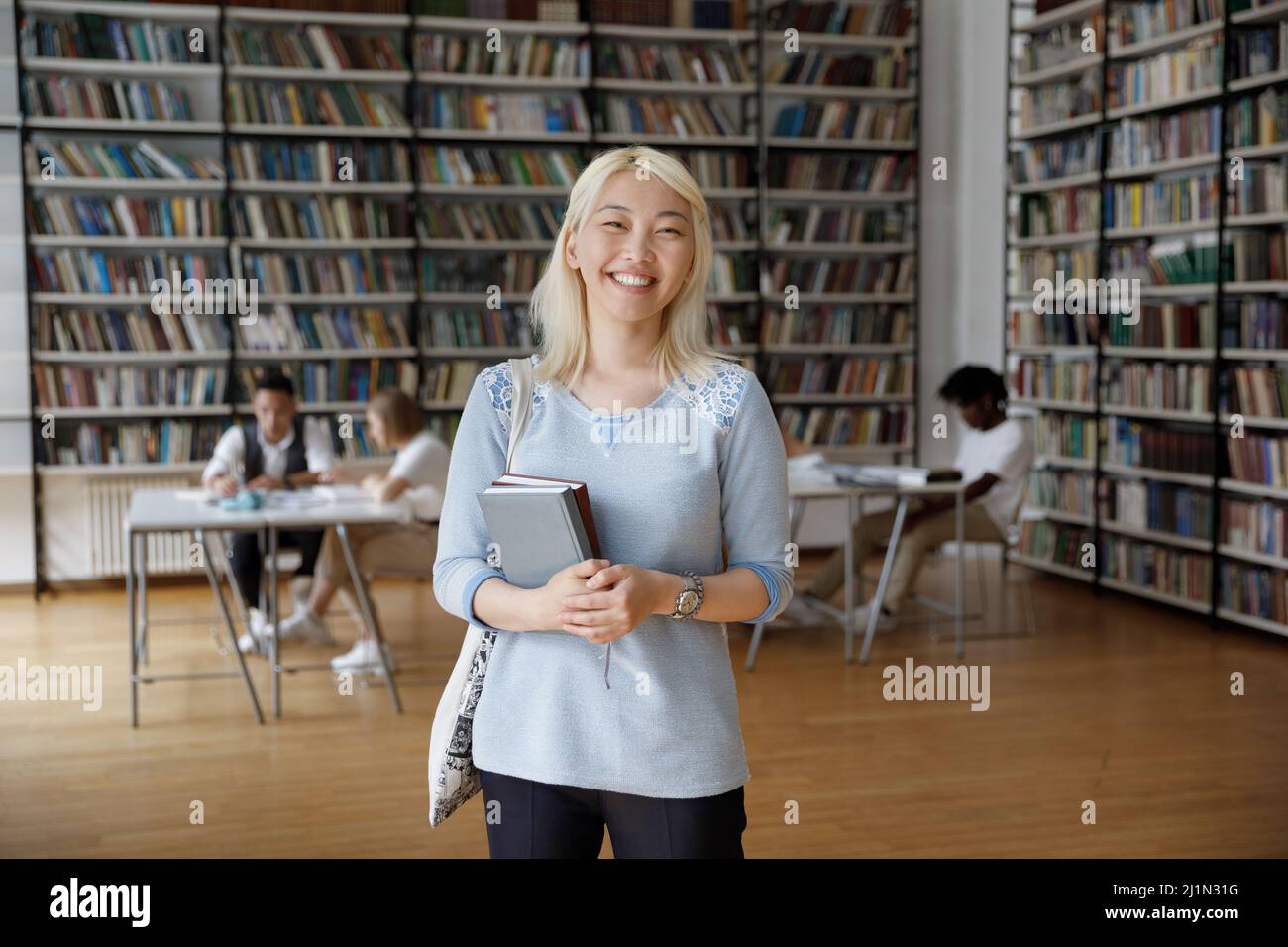 Retrato de una atractiva estudiante asiática de pie en la biblioteca del campus Foto de stock