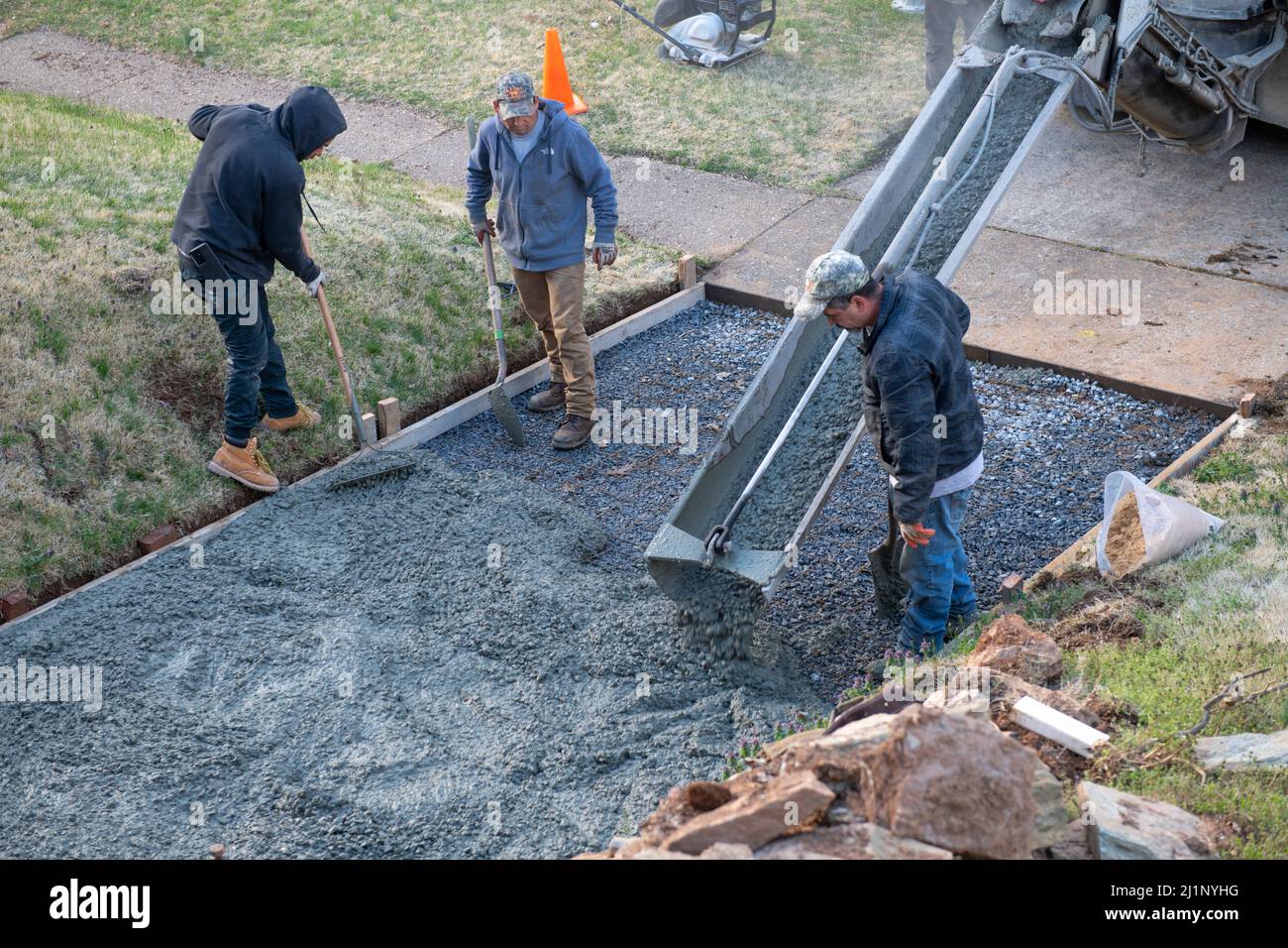 Los trabajadores que vierten un nuevo camino en una casa en Maryland EE.UU. El hormigón se coloca sobre malla de alambre y grava para hacer la superficie terminada fuerte Foto de stock