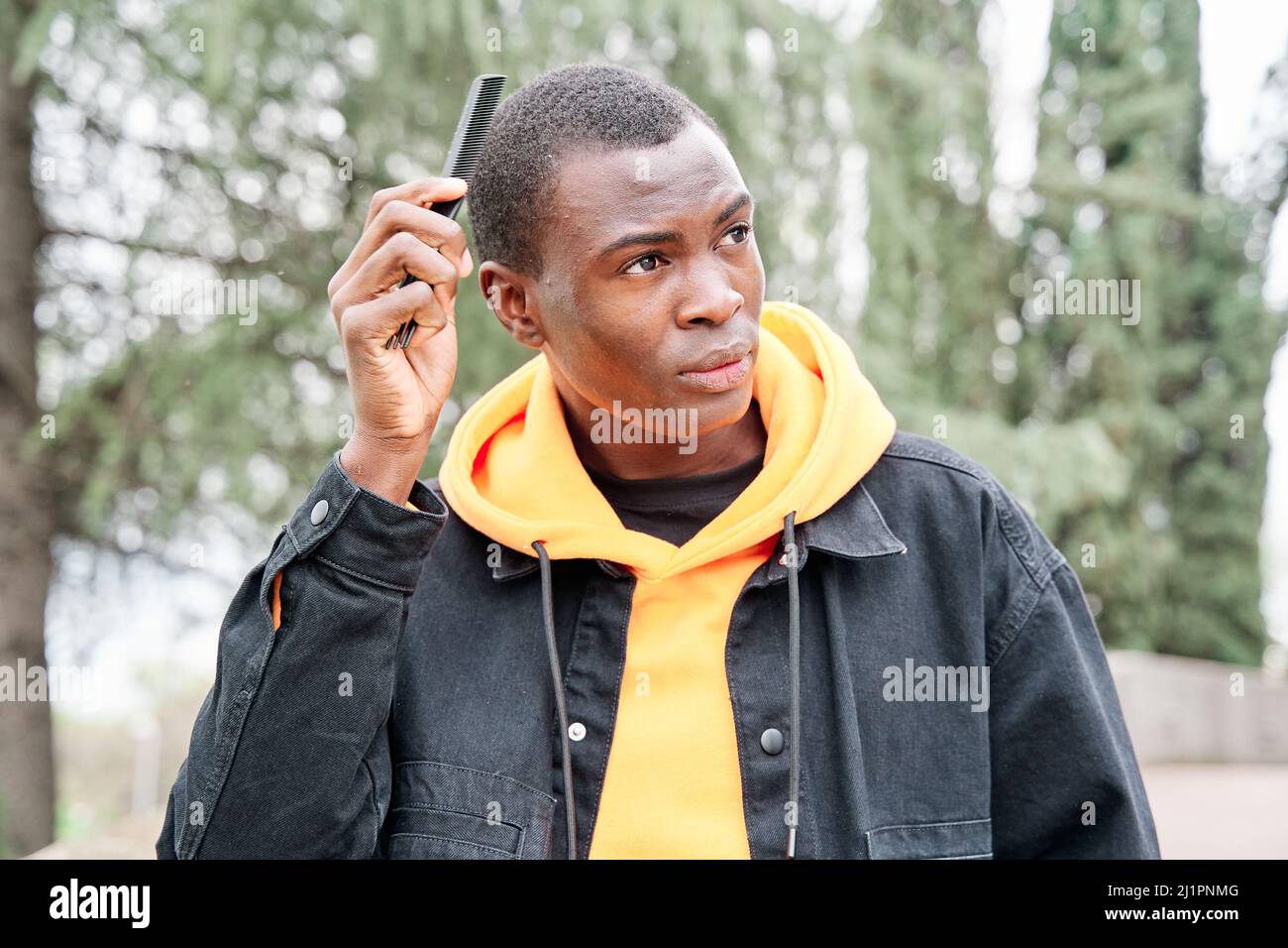 Traer navegador láser Un joven afroamericano negro con sudadera amarilla, chaqueta negra, pela su  cabello en la ciudad Fotografía de stock - Alamy