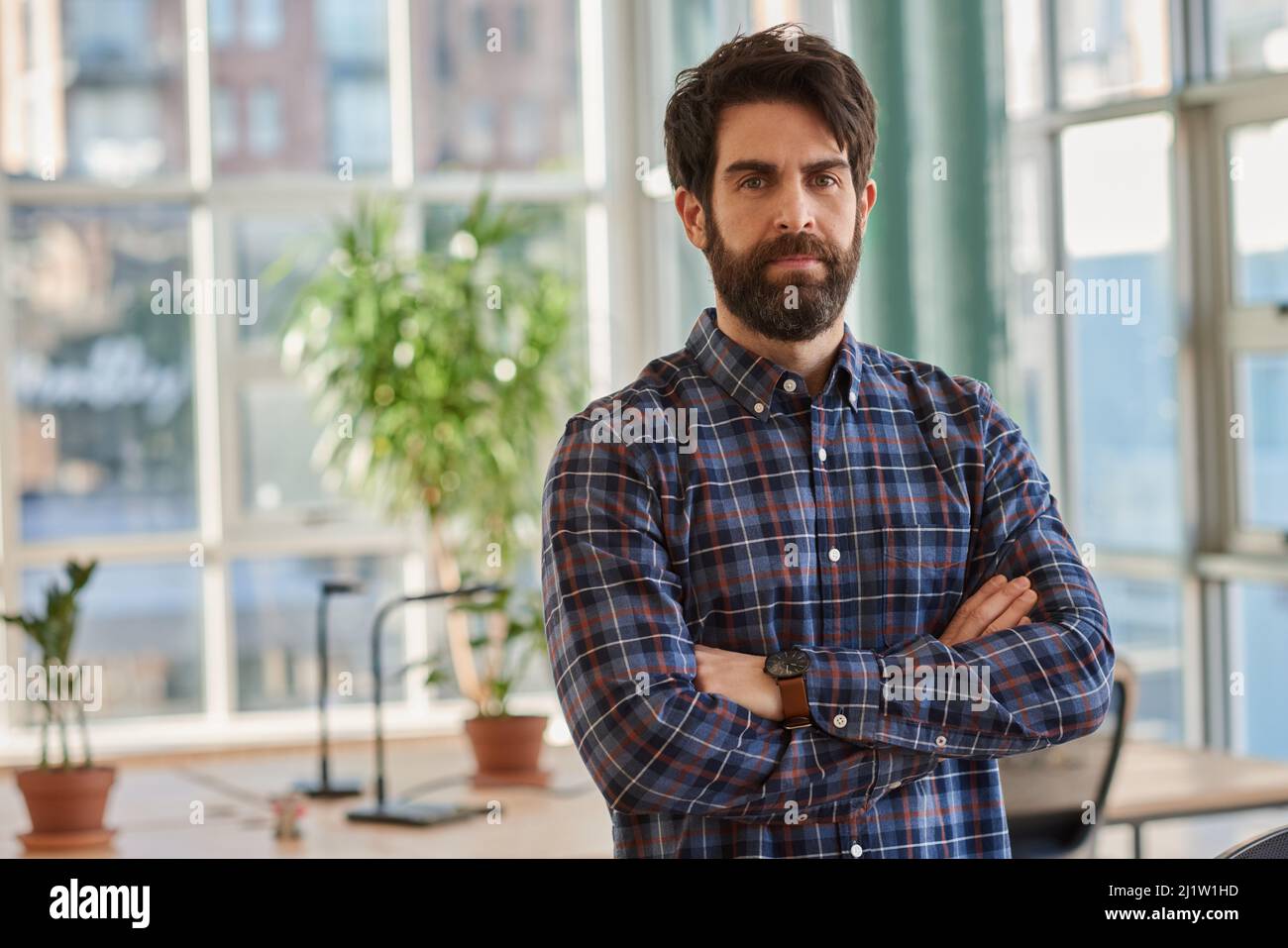 Un hombre de negocios confiado de pie con sus brazos cruzados en una oficina Foto de stock