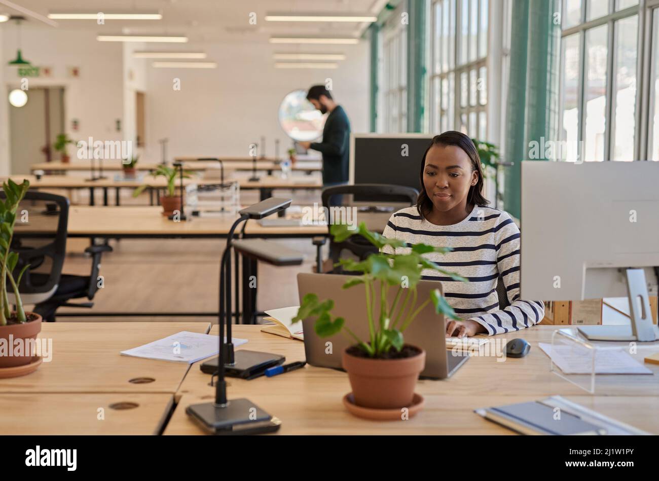 Joven empresaria africana enfocada trabajando en su escritorio en una oficina Foto de stock