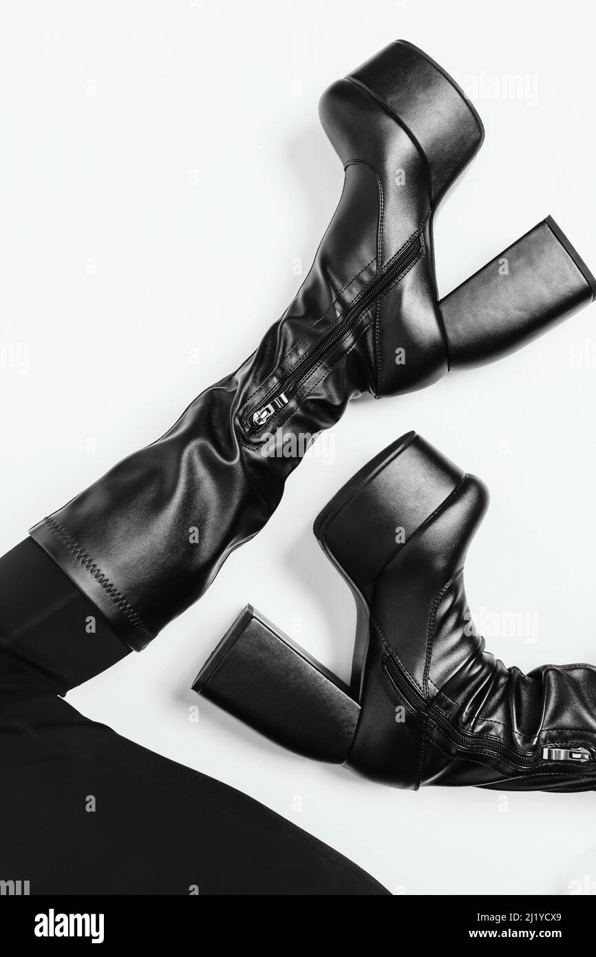 Piernas delgadas para mujer en botas de cuero negro sobre fondo blanco. Zapatos modernos en plataforma alta. Colección de moda de bots para las mujeres fuertes de hoy. Antecedentes. Foto de stock