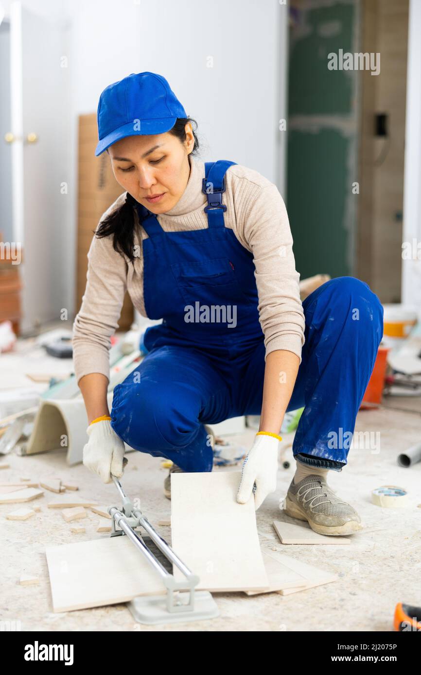 Un trabajador corta azulejos con un cortador de azulejos.