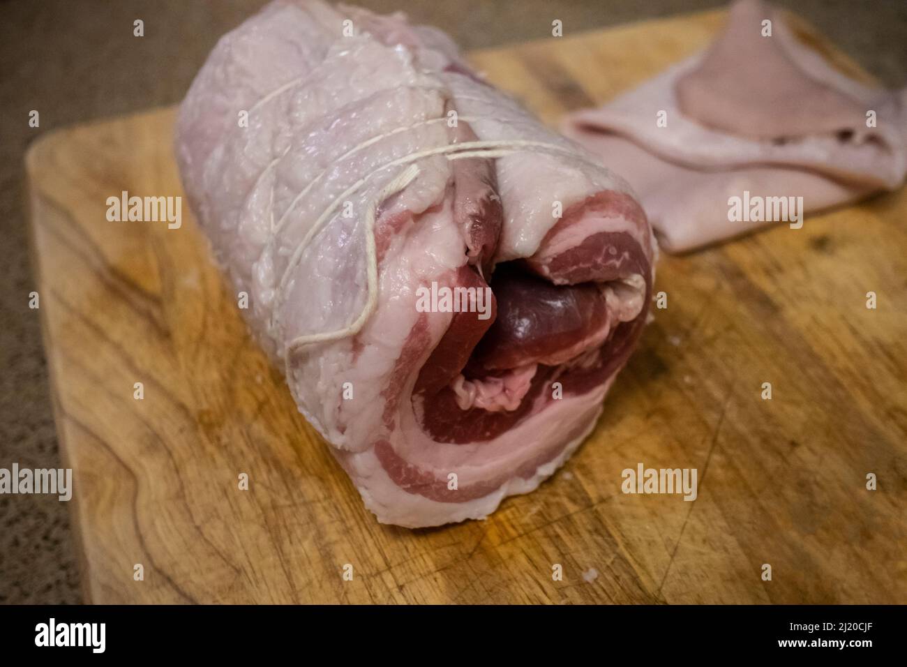 Primer plano, enfoque selectivo en un rollo de chashu de cerdo sin cocinar, a punto de ser cocinado para el ramen tonkotsu Foto de stock