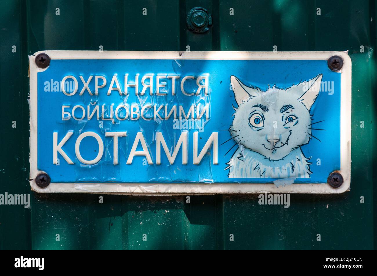 Kiev, Ucrania - 3 de julio de 2021: Una señal azul colocada en la valla frente a una casa suburbana. El letrero dice 'custodiado por gatos de combate'. Hay un drawin Foto de stock