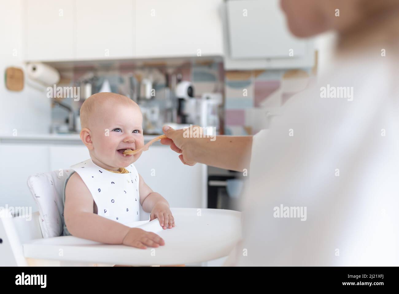 la primera alimentación del bebé, la mamá alimenta a un bebé con una cuchara Foto de stock