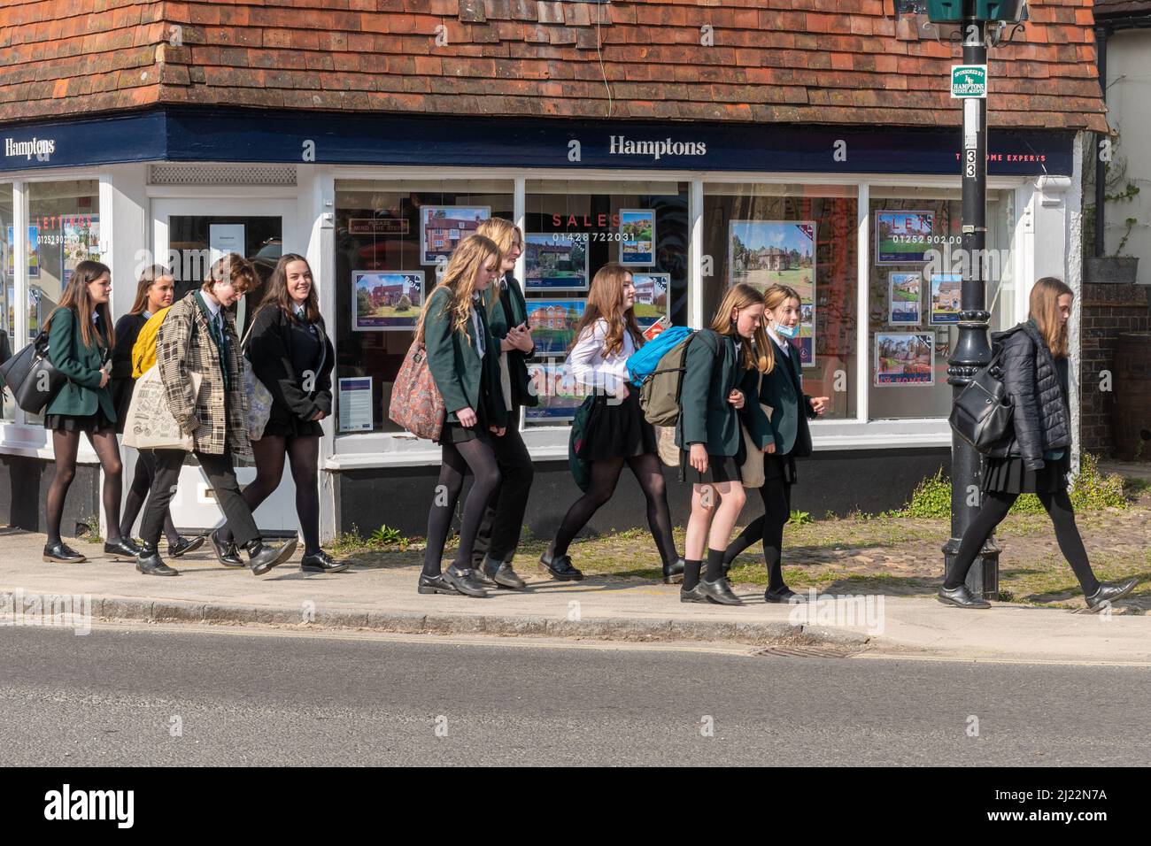 Niños de secundaria alumnos estudiantes que caminan a casa después de la escuela a través del centro Liphook, Hampshire, Inglaterra, Reino Unido Foto de stock
